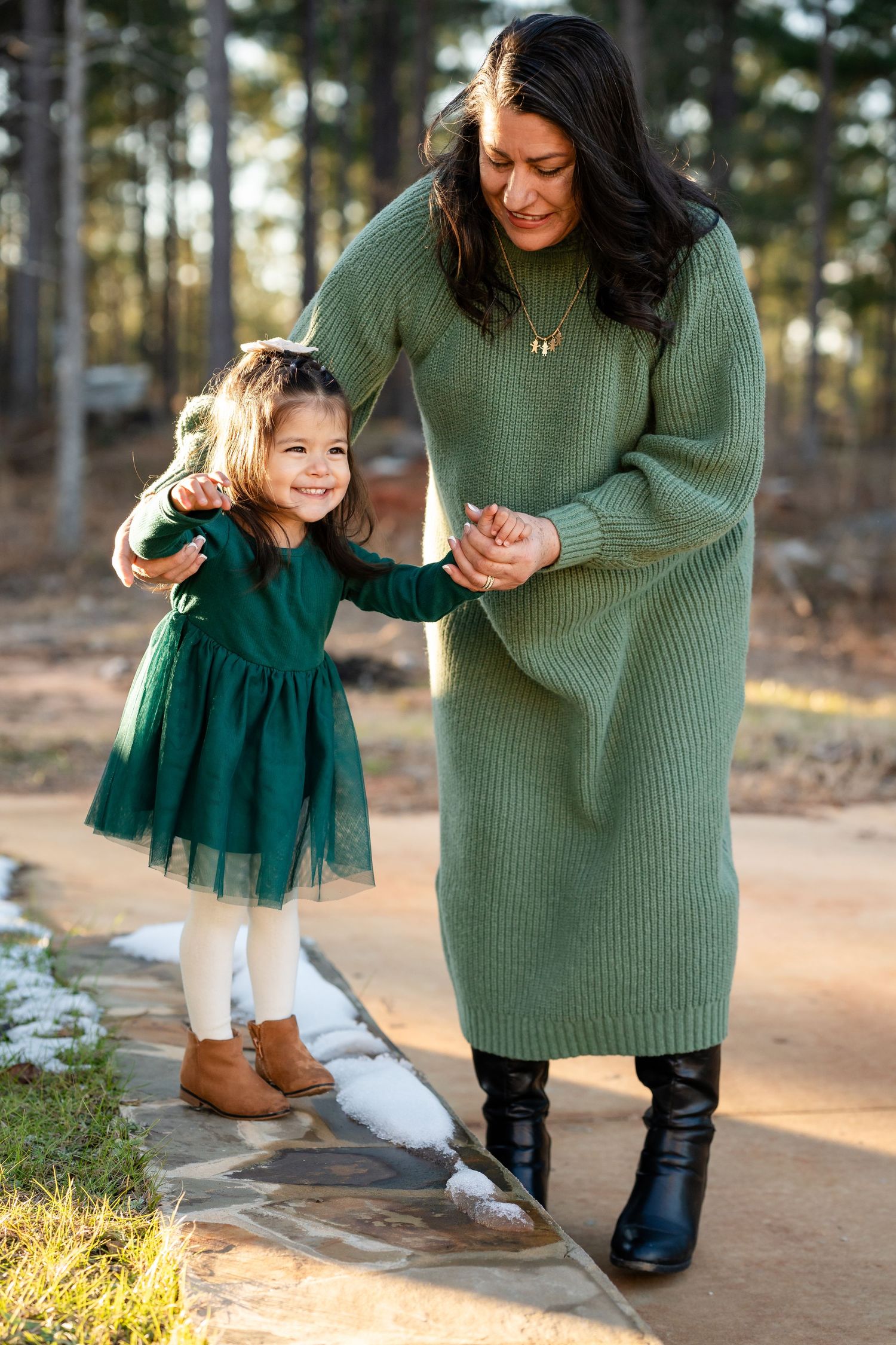 Sweet moment between parent and child in matching green outfits outdoors.