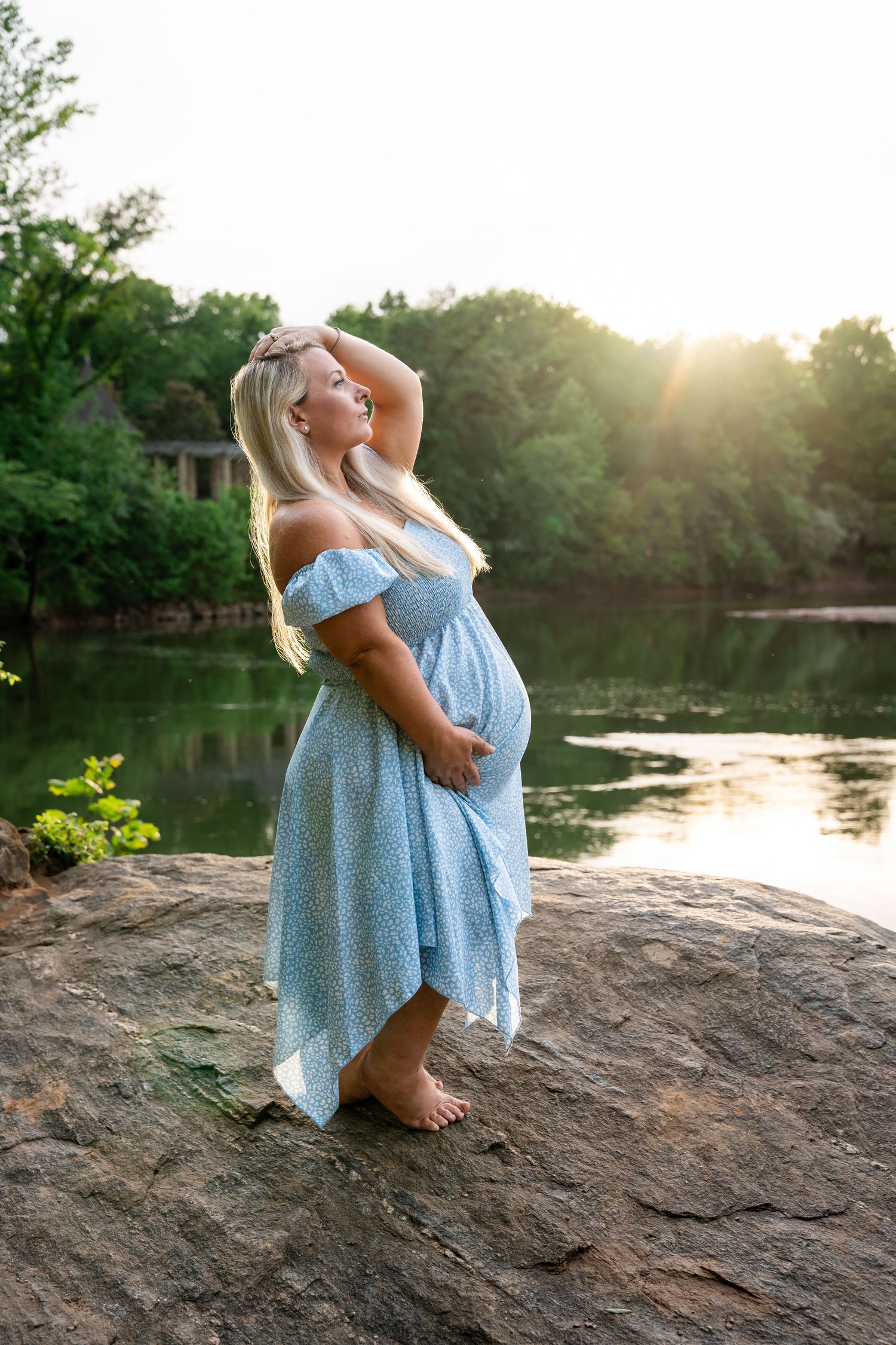 Scenic lakeside photoshoot with rocky outcrop and sunset reflections on water.