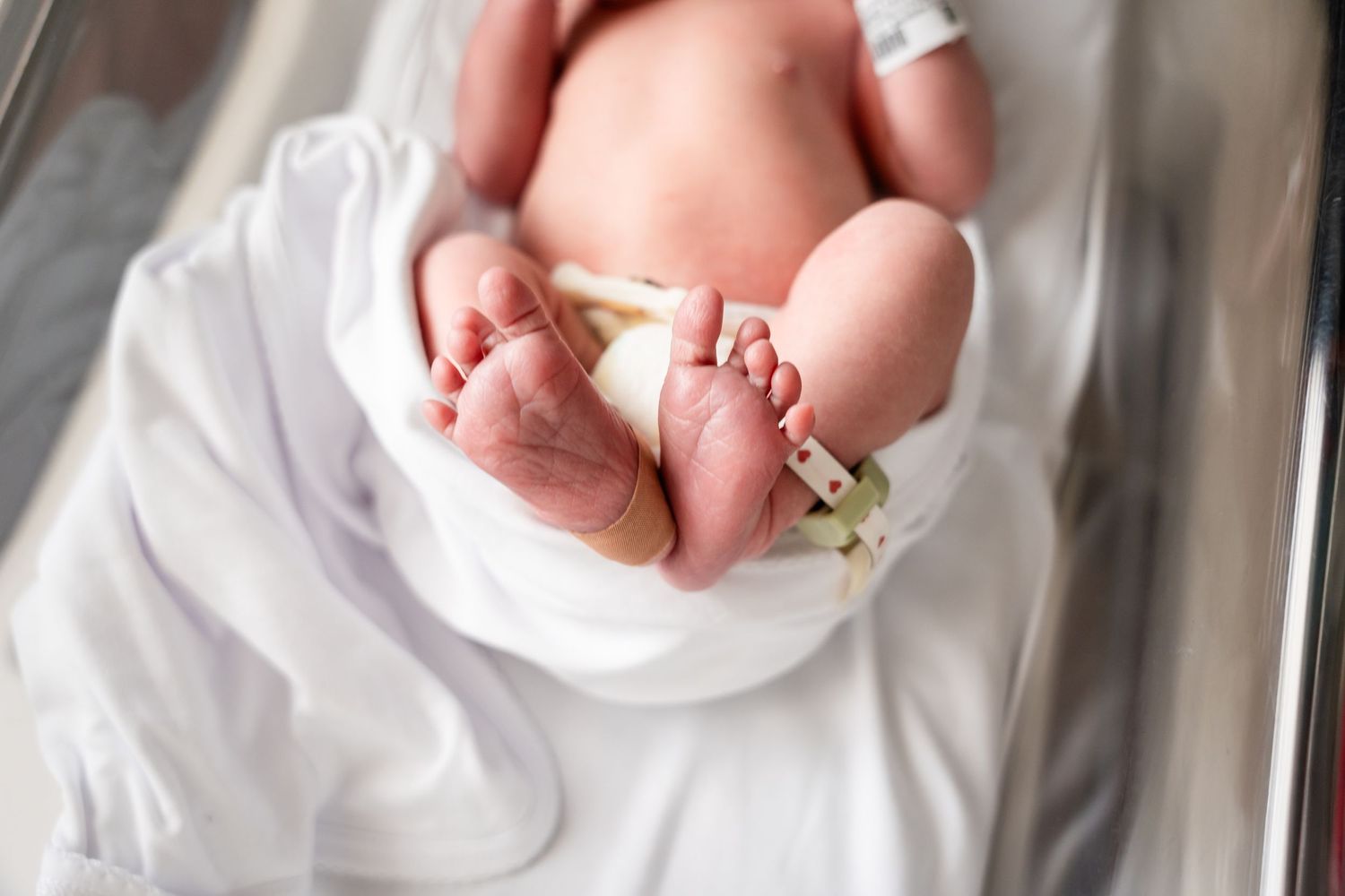 Hospital identification tag visible on sleeping newborn's foot.