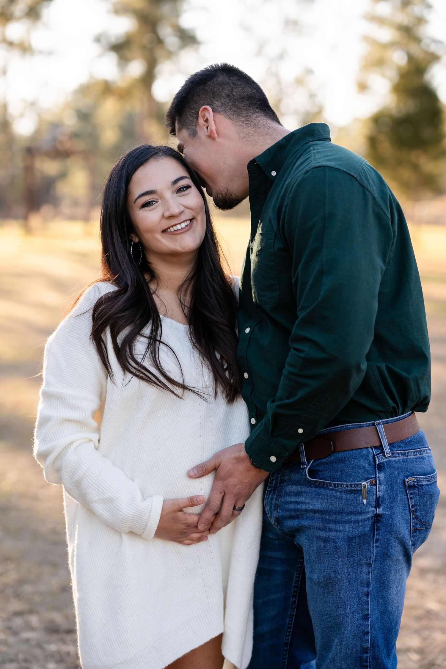 Couple enjoying a romantic outdoor photoshoot in a park setting during golden hour.