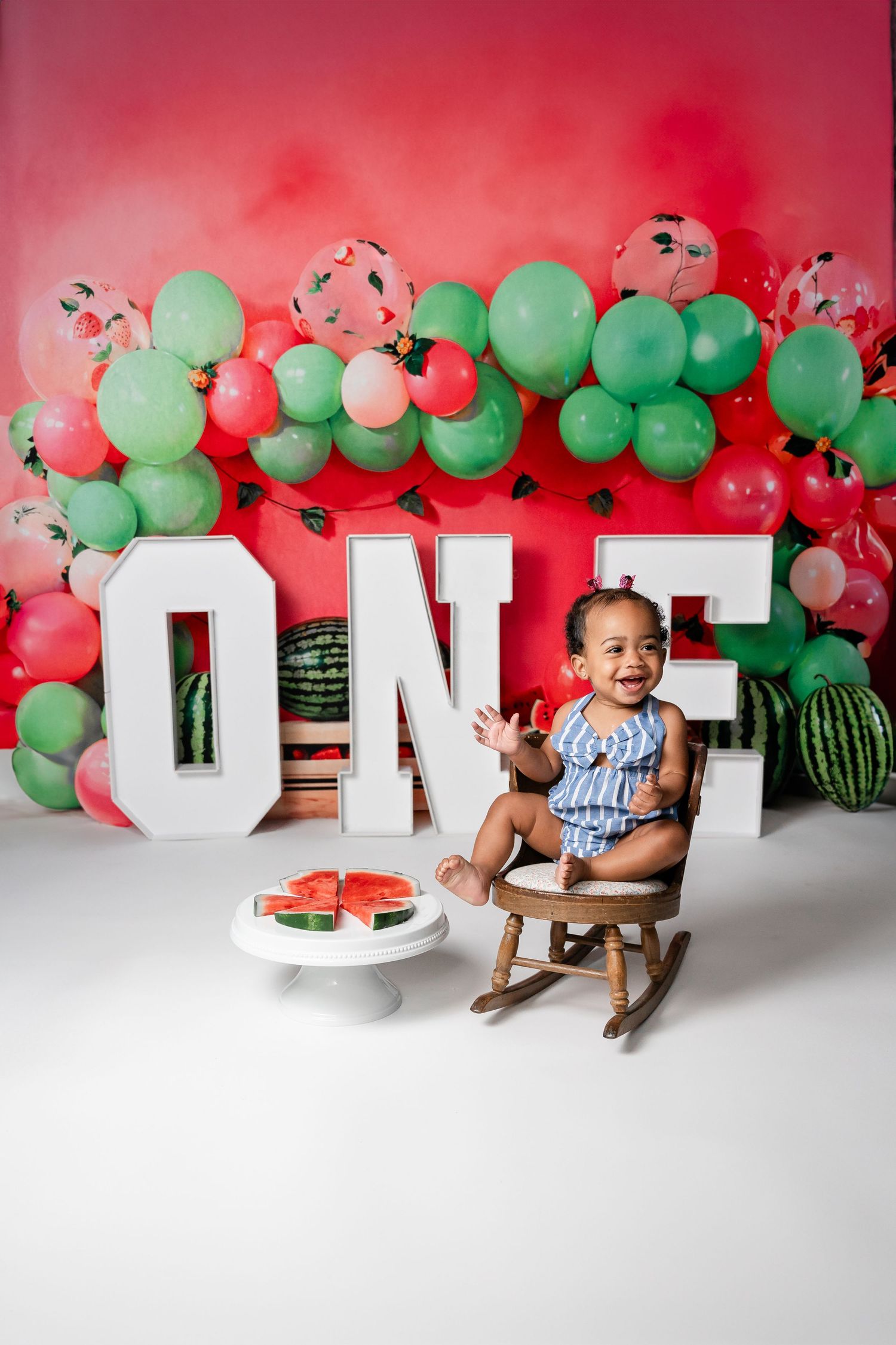 Watermelon themed first birthday setup with red and green balloon garland and ONE letters.