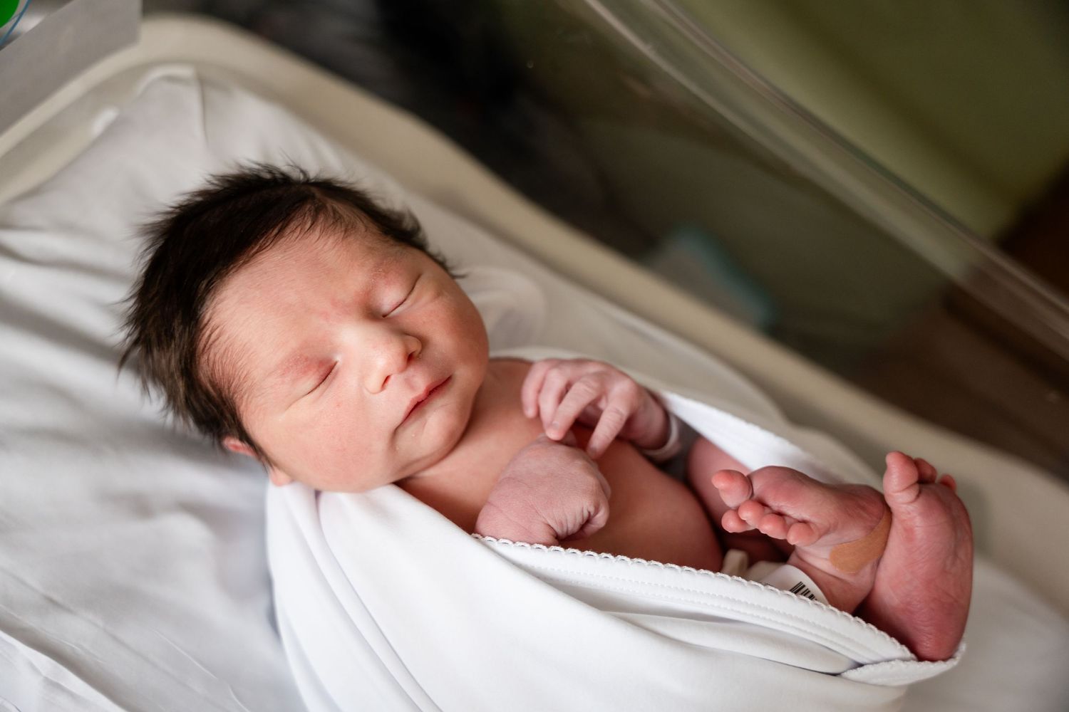 Close-up of sleeping newborn baby in hospital setting.