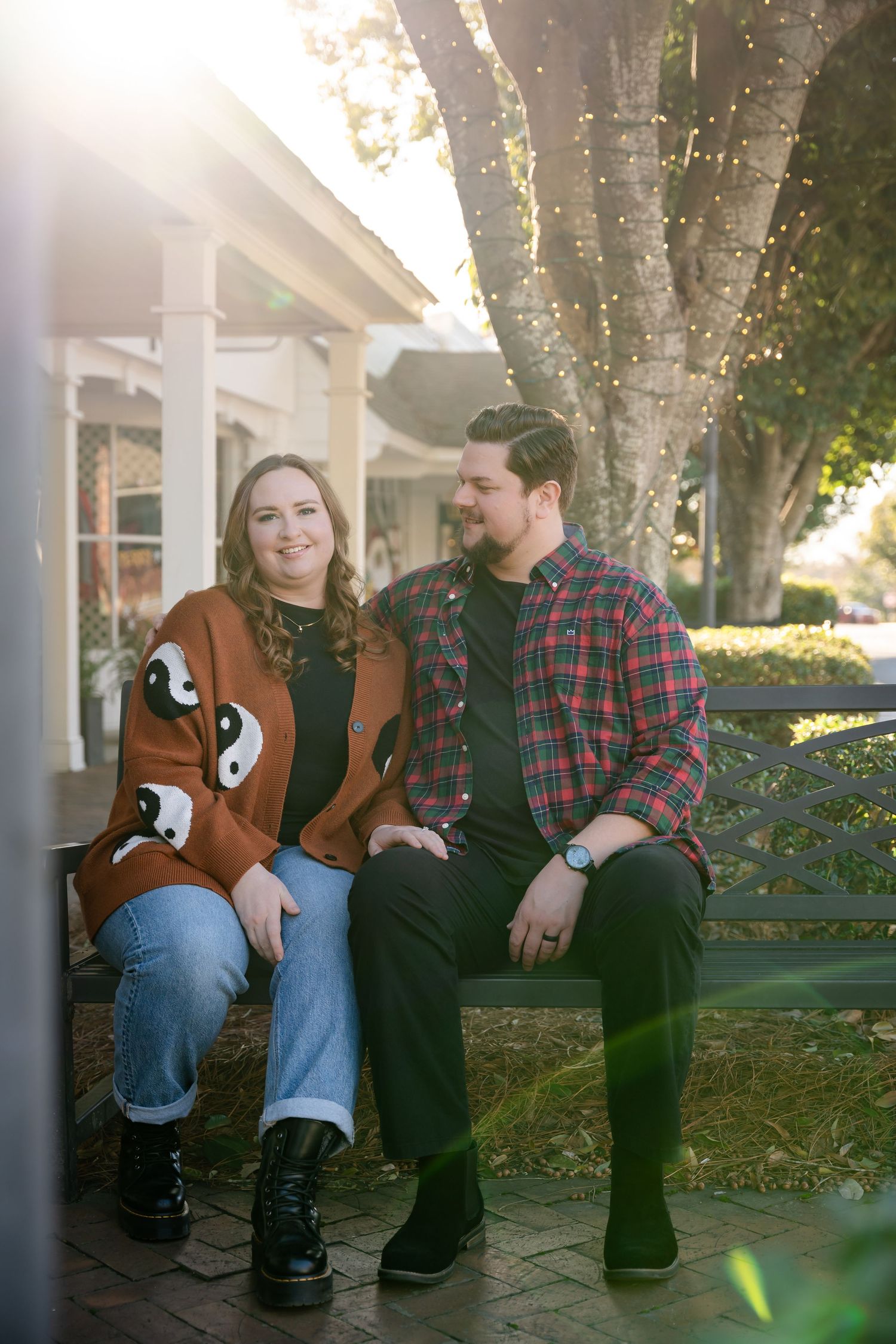 Couple sitting together on bench under trees during autumn.
