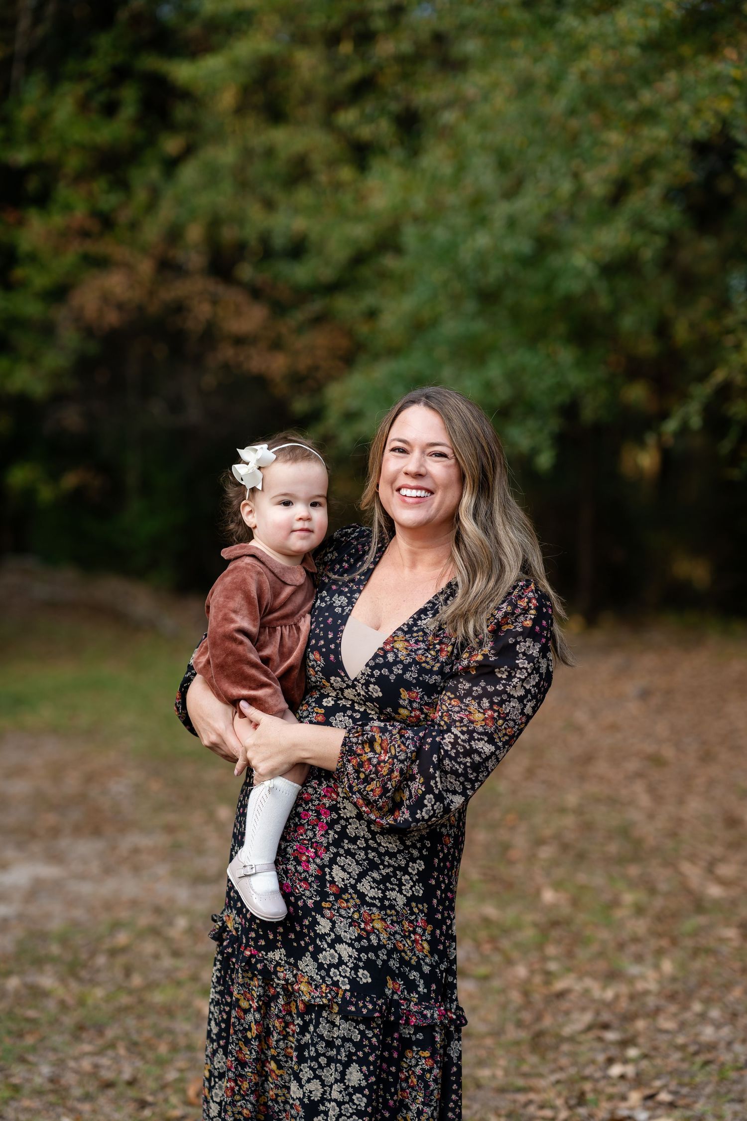 Mother and toddler share joyful laughter during outdoor autumn photoshoot.