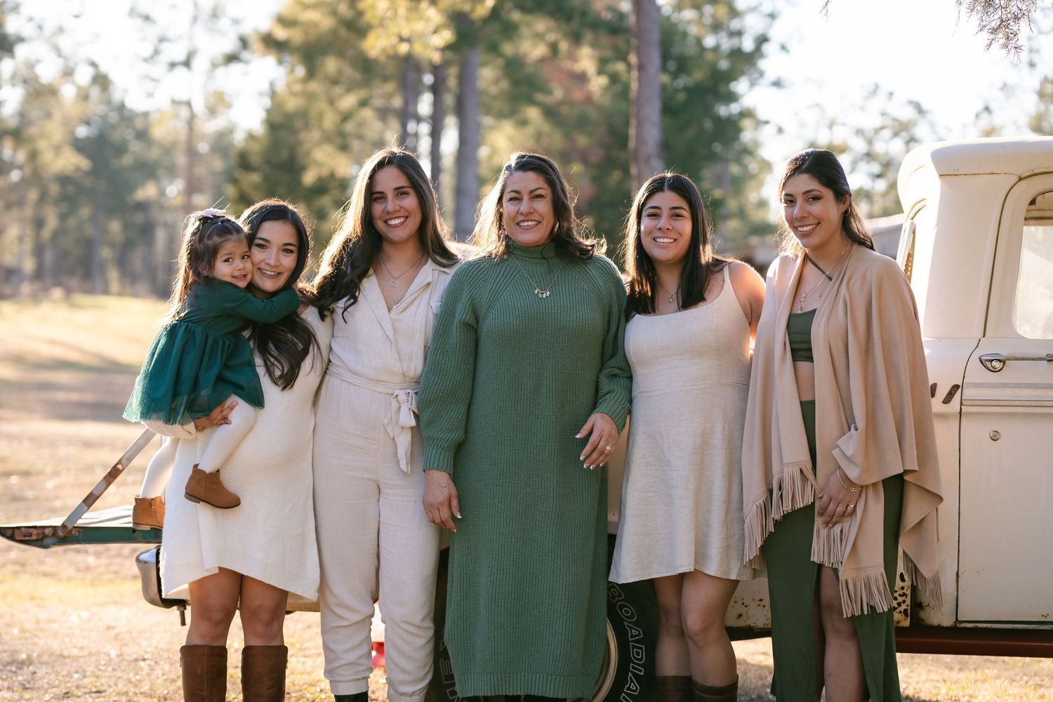 Group poses together by vintage truck wearing coordinated neutrals and green.