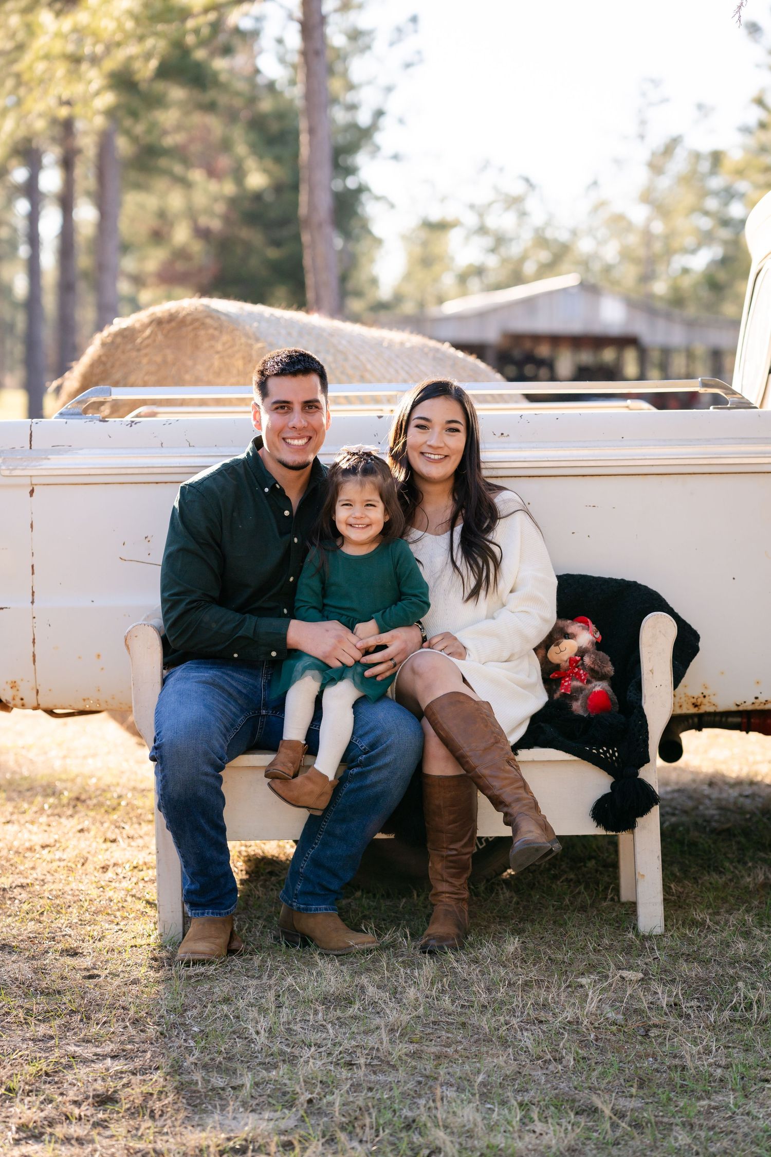 Family seated together on white bench in outdoor setting during golden hour.