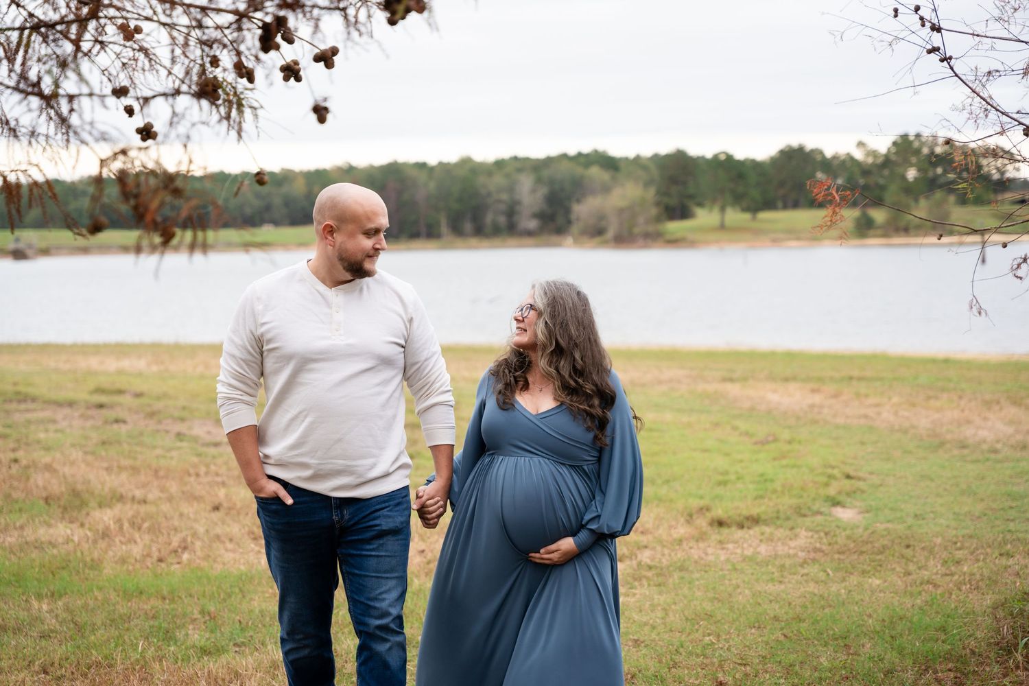 Couple shares tender moment while walking along lakeside path during photo session.