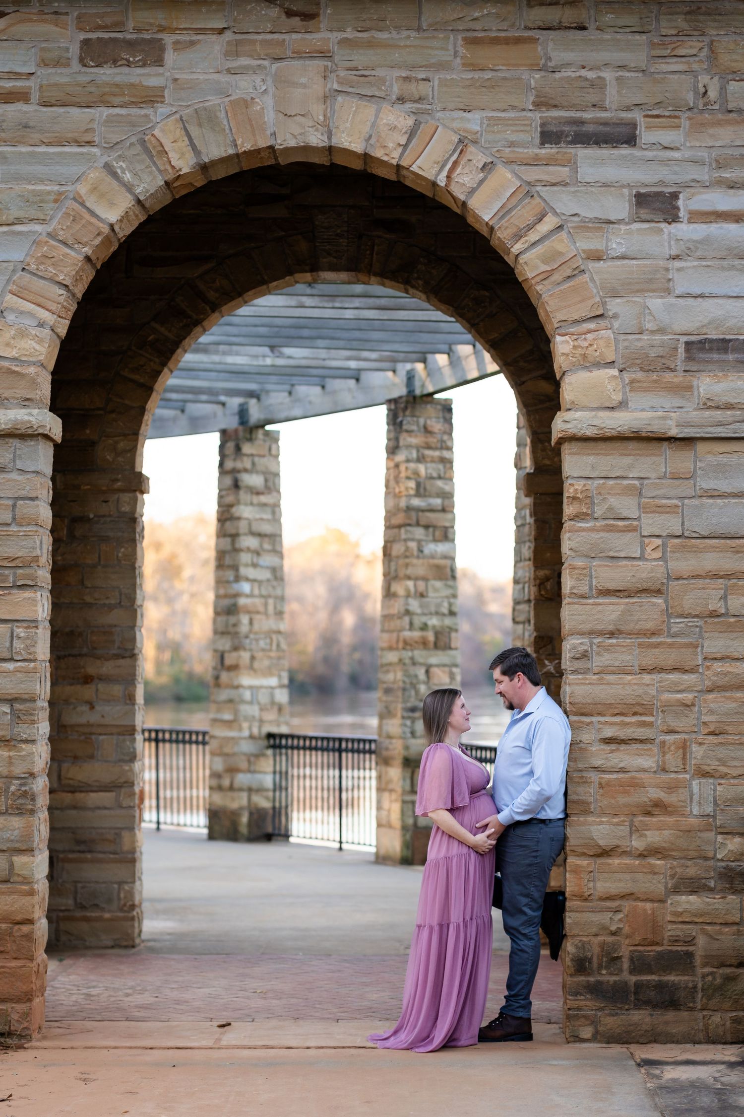 A romantic couple photoshoot under stone archways at sunset.