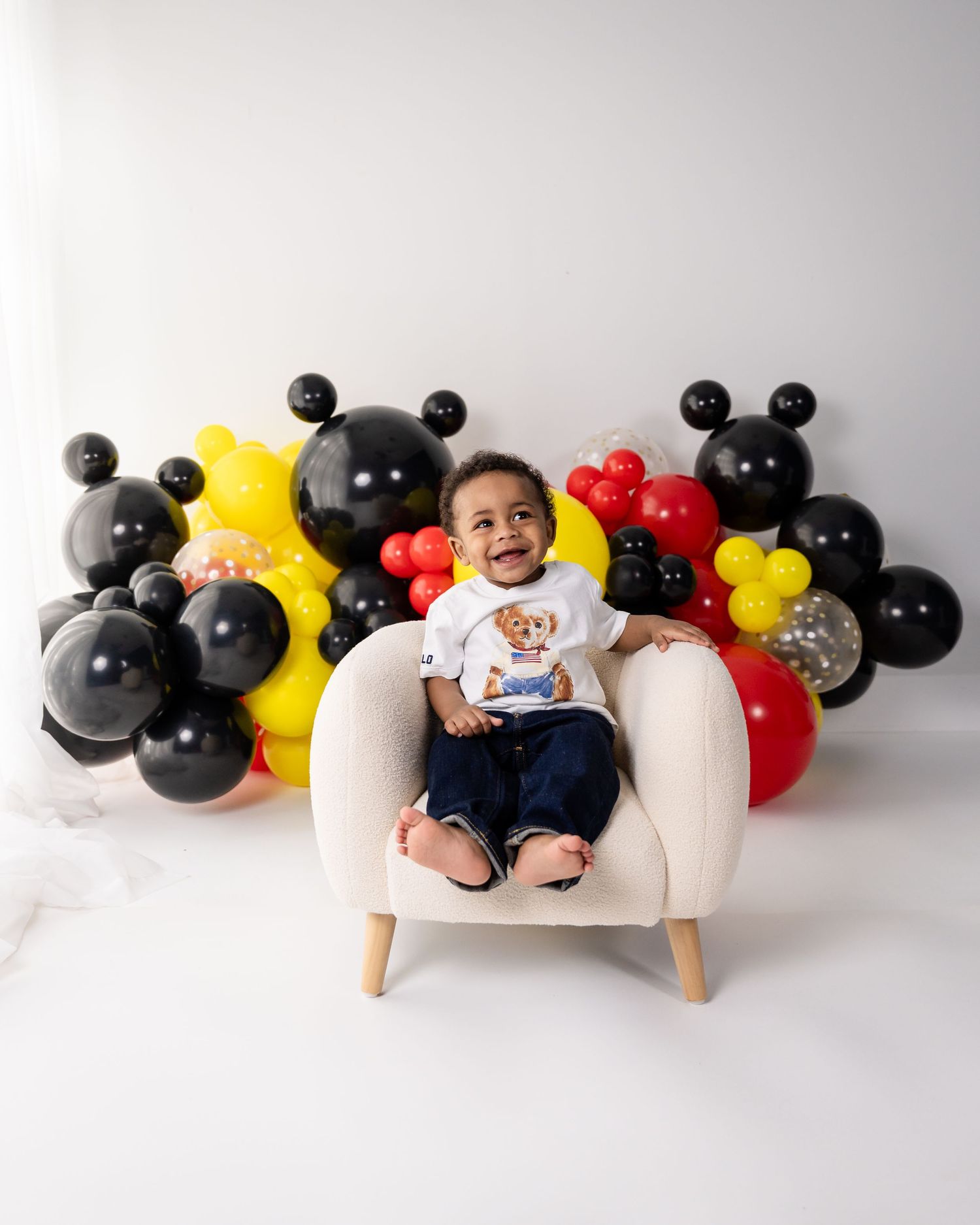 Mickey Mouse themed birthday setup with black and yellow balloons against white background.