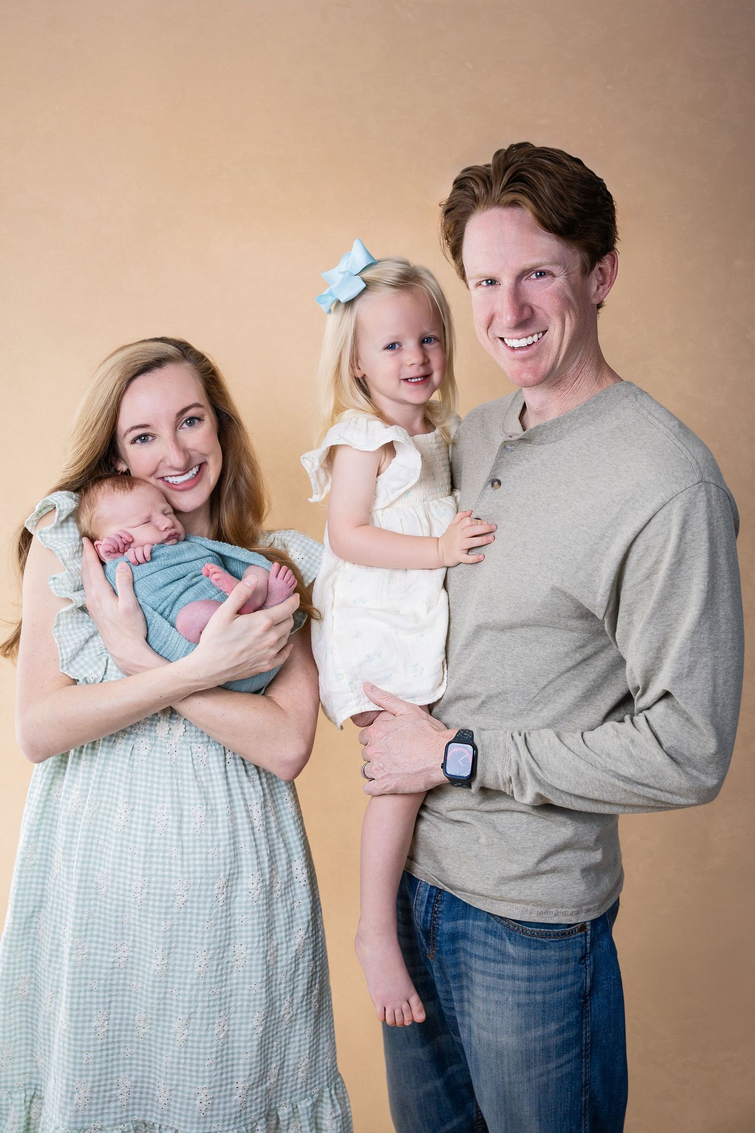 Family portrait series showing parents in casual clothes bonding with their newborn.