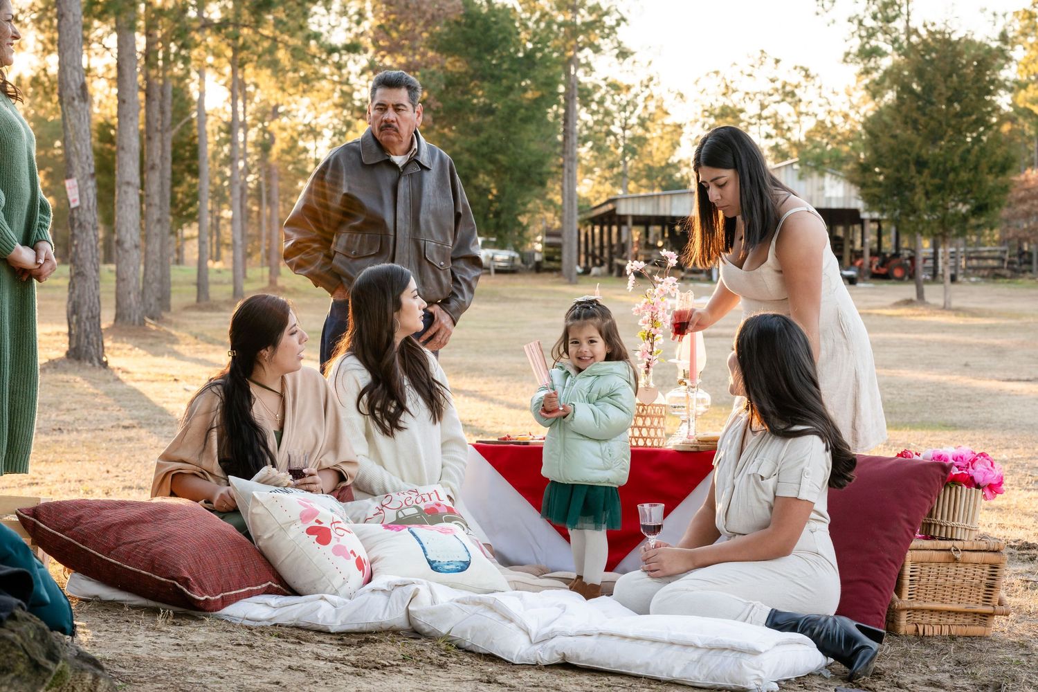 Group gathering for casual outdoor picnic with red pillows and blankets.
