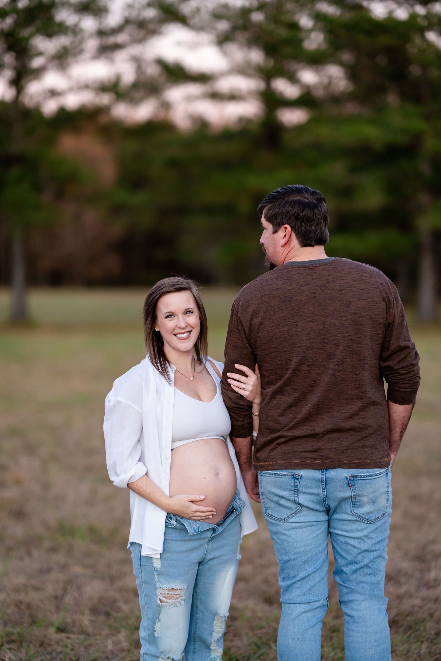 A maternity photoshoot in casual attire outdoors.