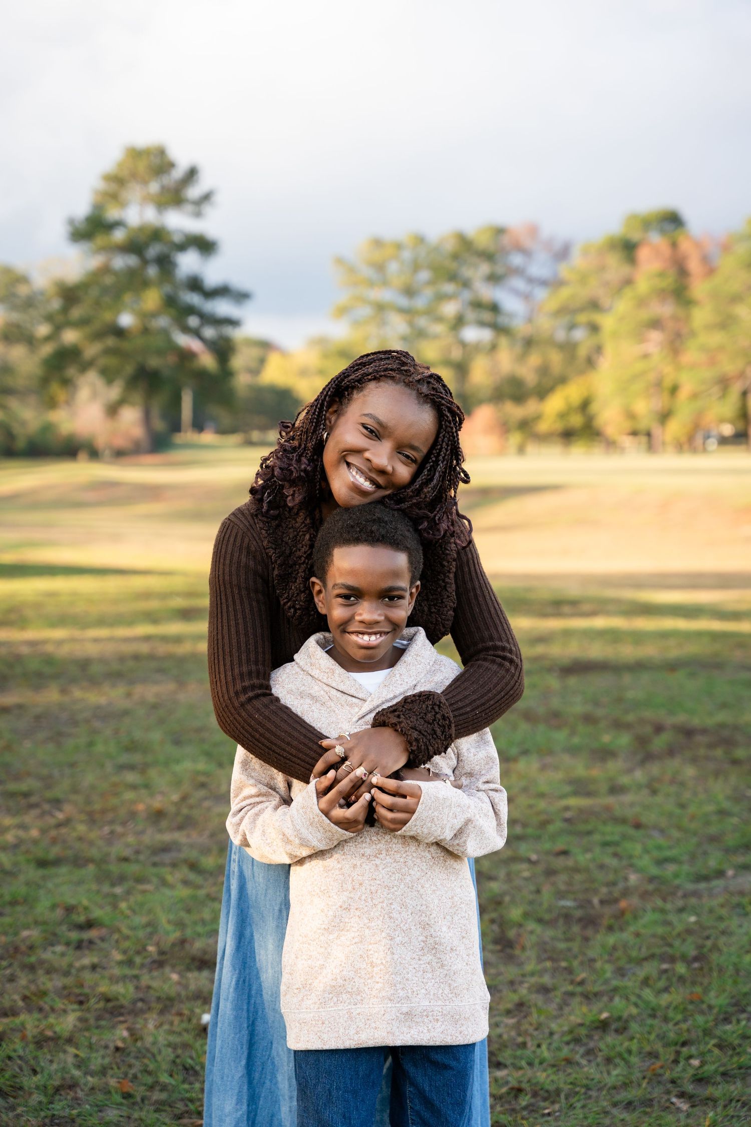 Sweet embrace between two people captured in a sunny field during autumn.