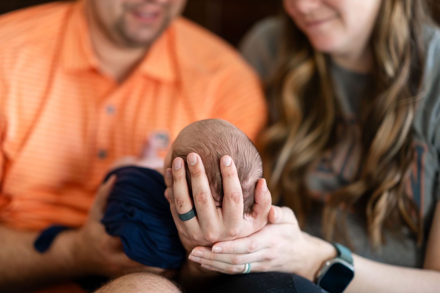 Parents sharing a tender moment with their newborn baby in natural light.