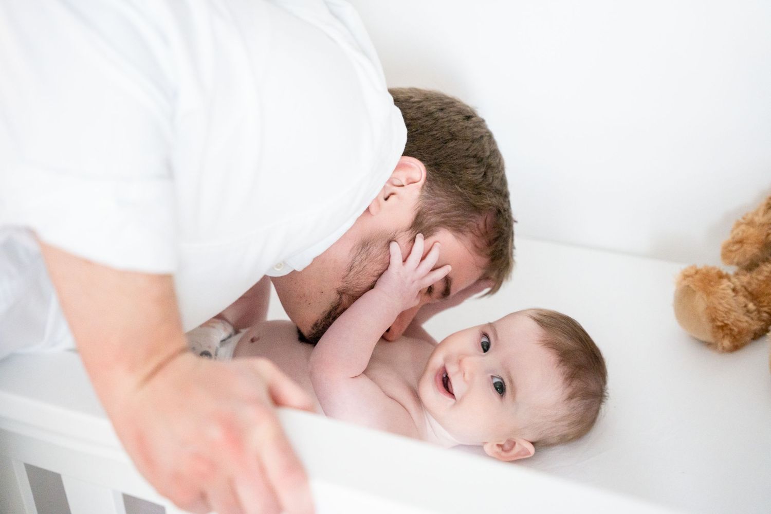 A tender moment captured on white bedding with joyful expressions.