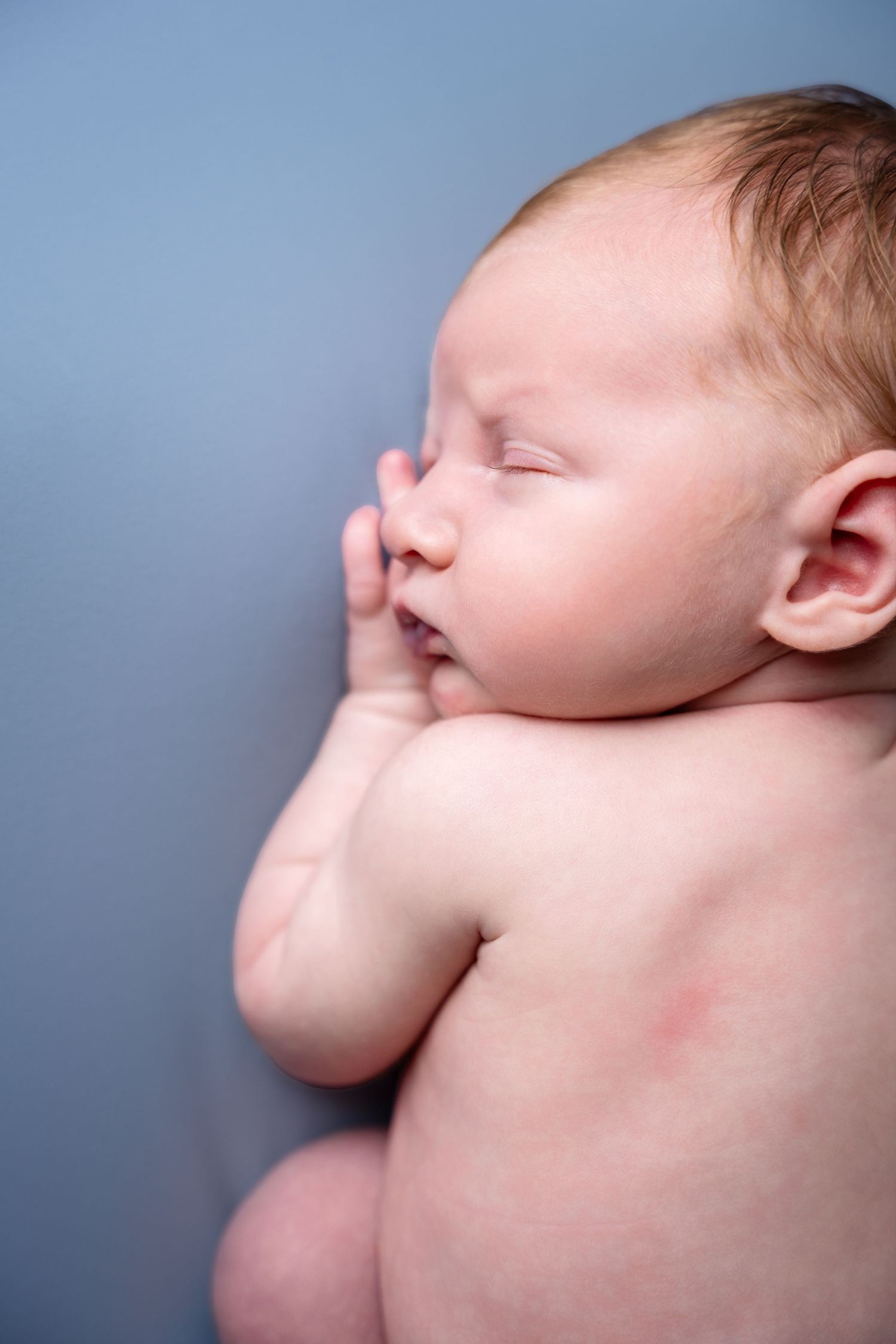 Close-up profile shots of a sleeping newborn baby against blue background.