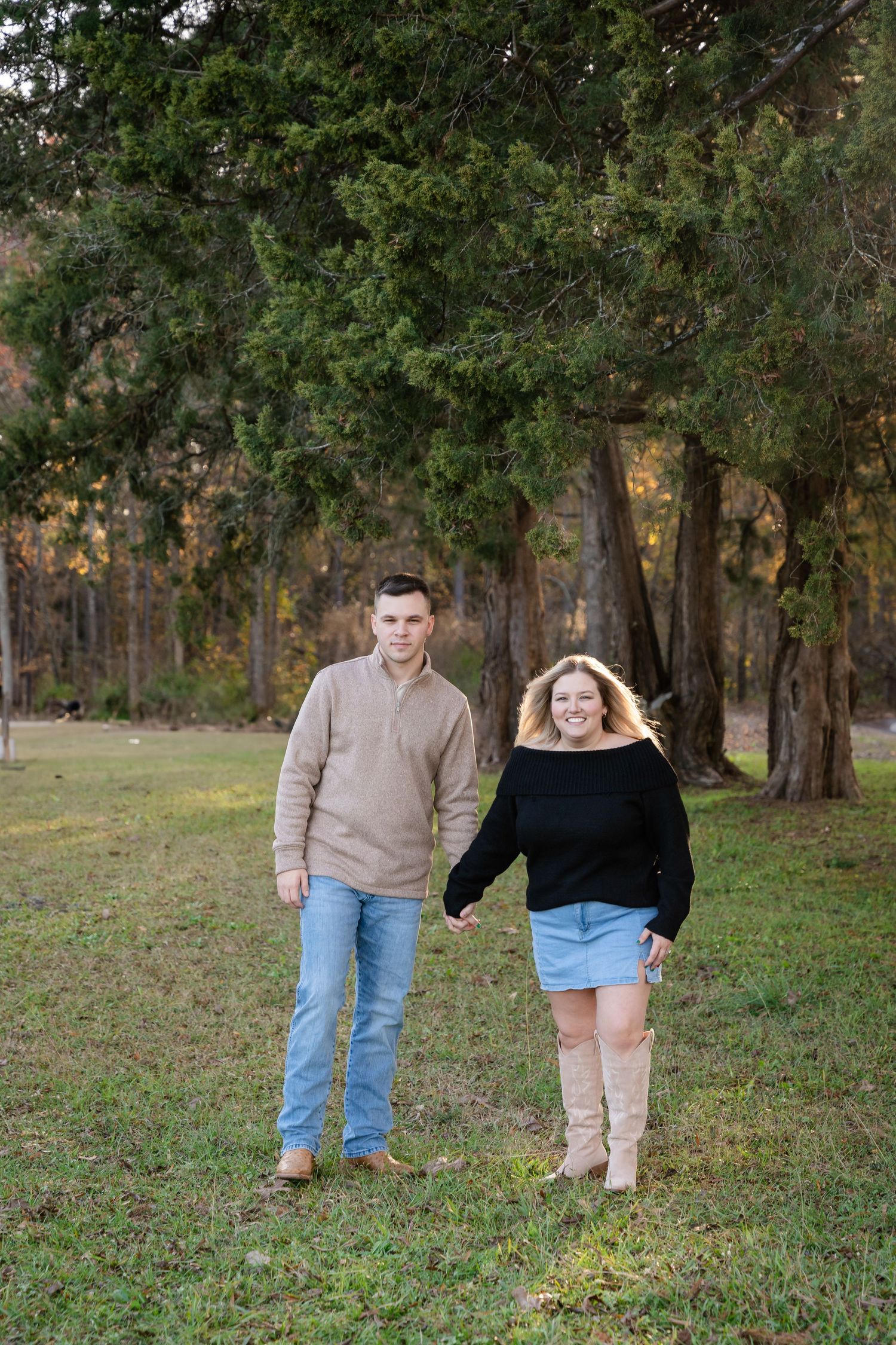 A couple walks together through a wooded park during autumn season.