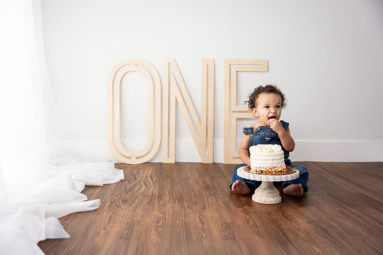 First birthday setup with wooden ONE letters and smash cake on table.