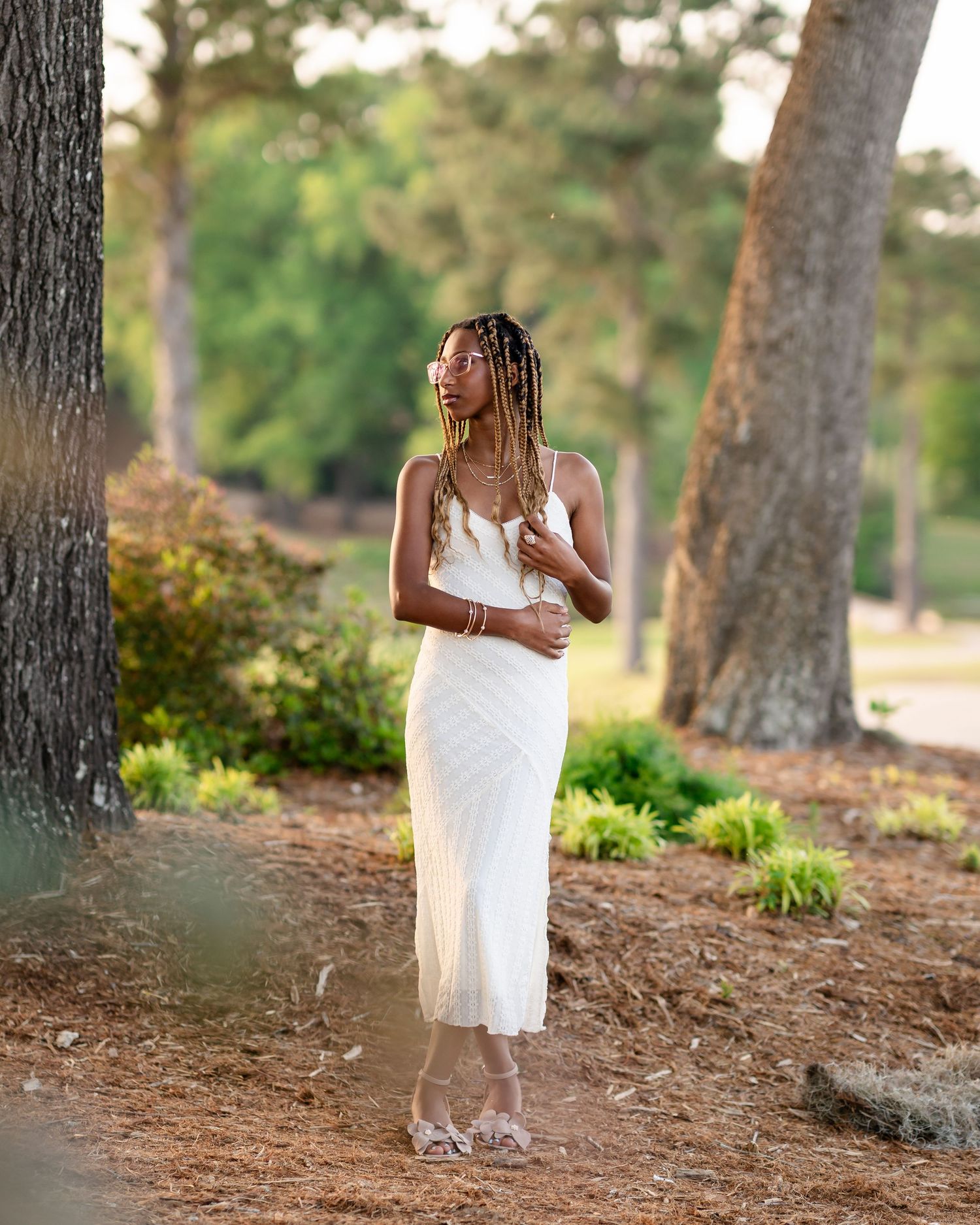 Person in a flowing white dress walks through a wooded forest path.