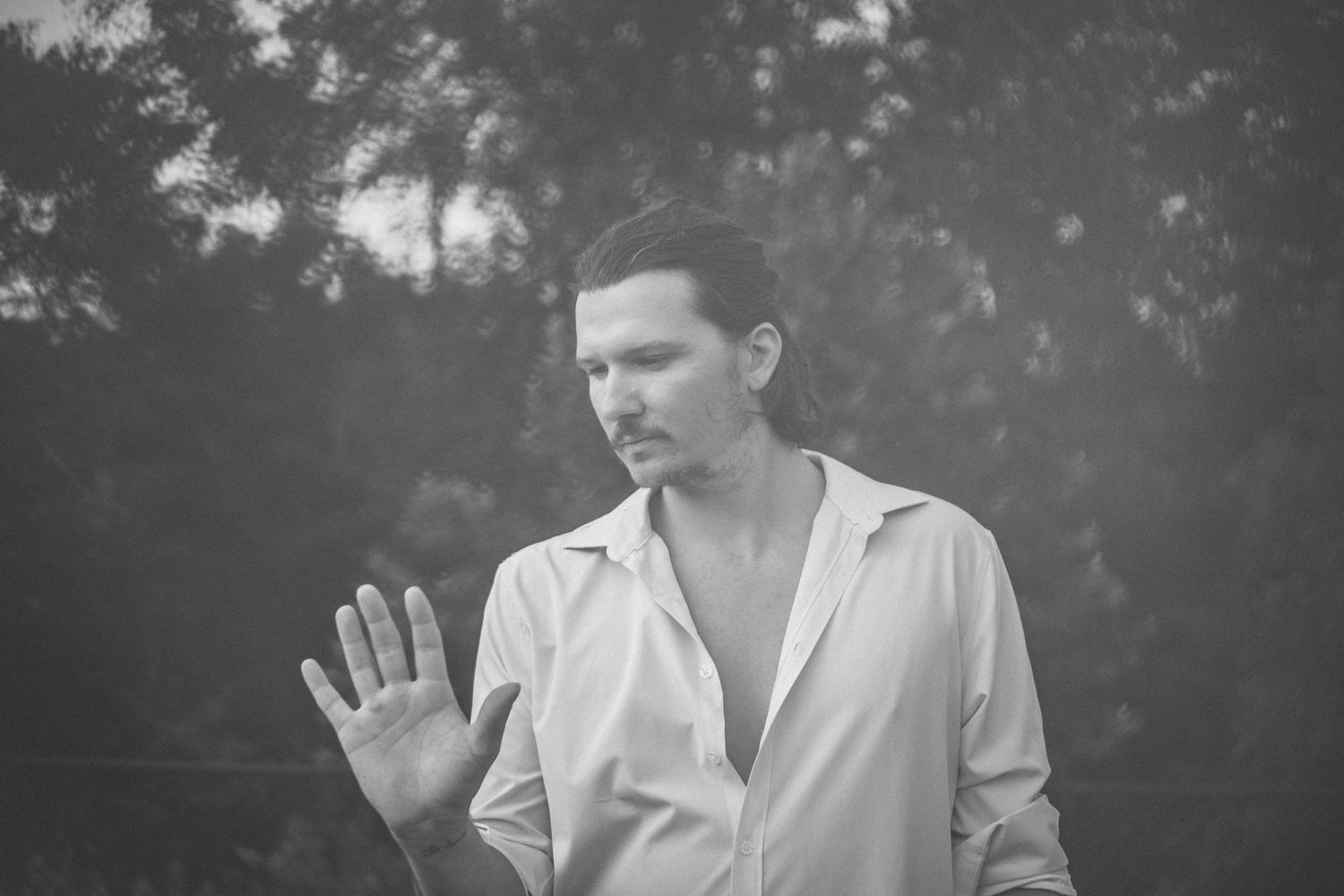 Black and white portrait of musician in white shirt with dramatic lighting.