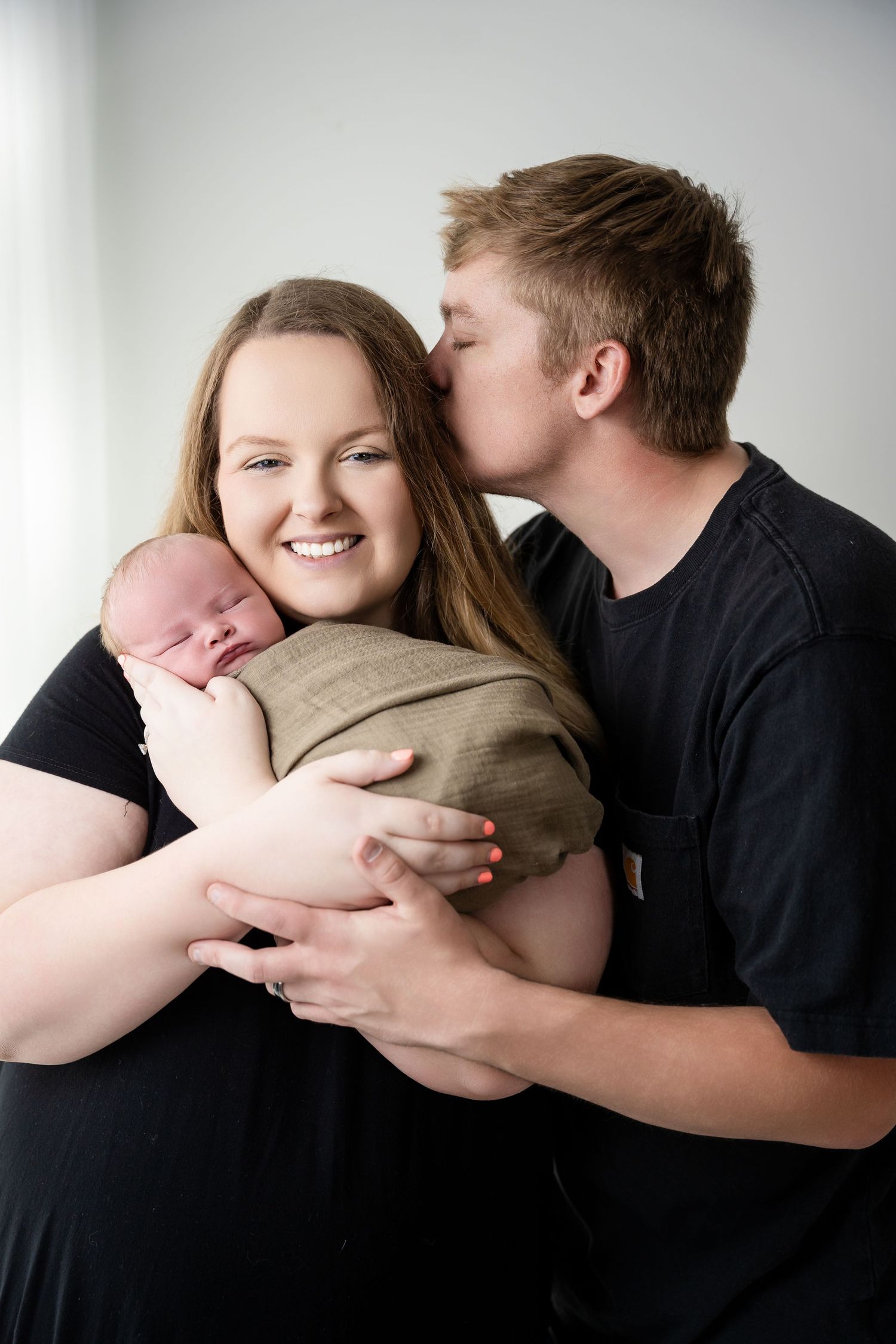 Intimate moment between couple sharing affection while holding their baby.