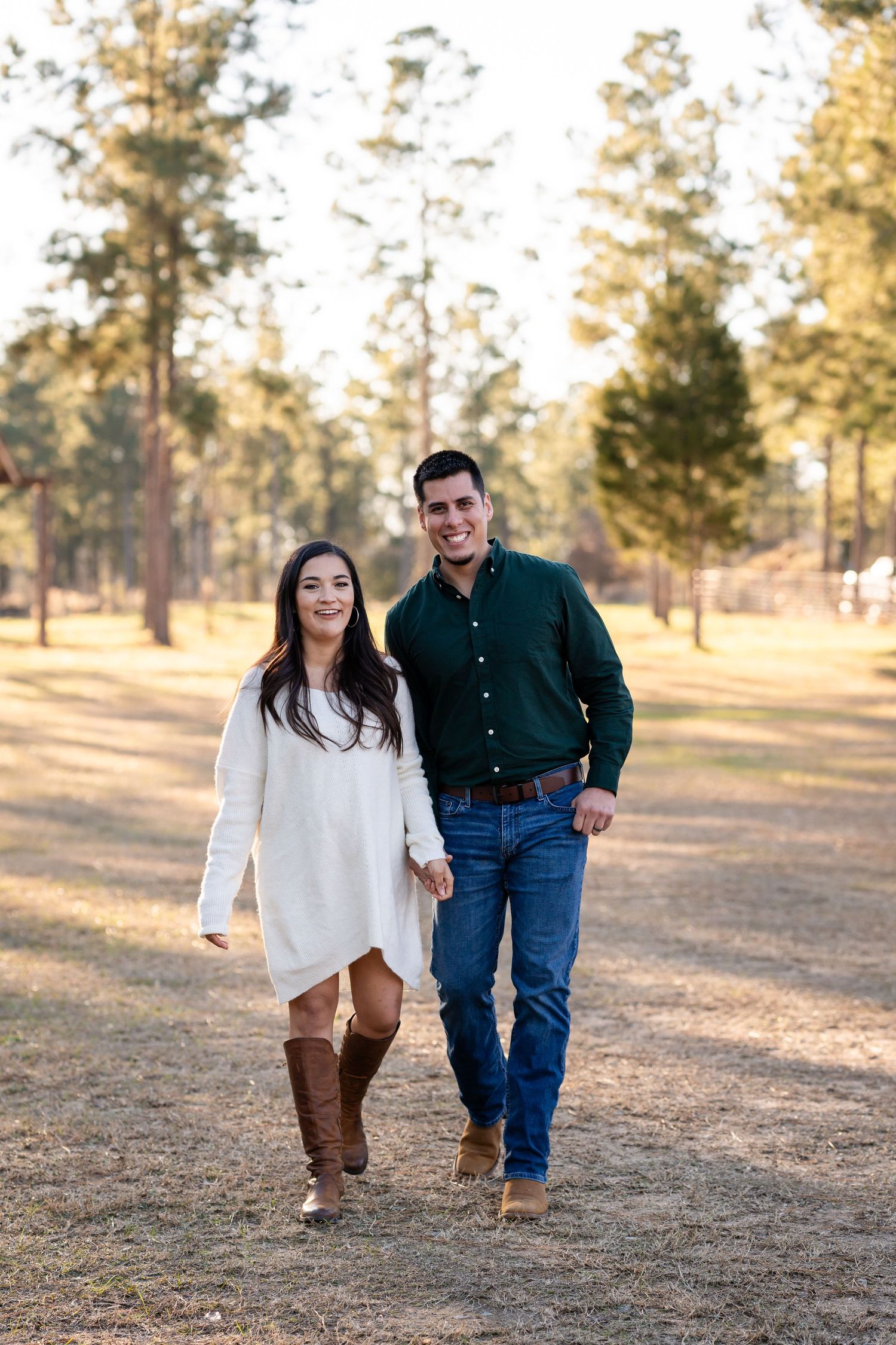 Couple walking and smiling together across an open field during golden hour.