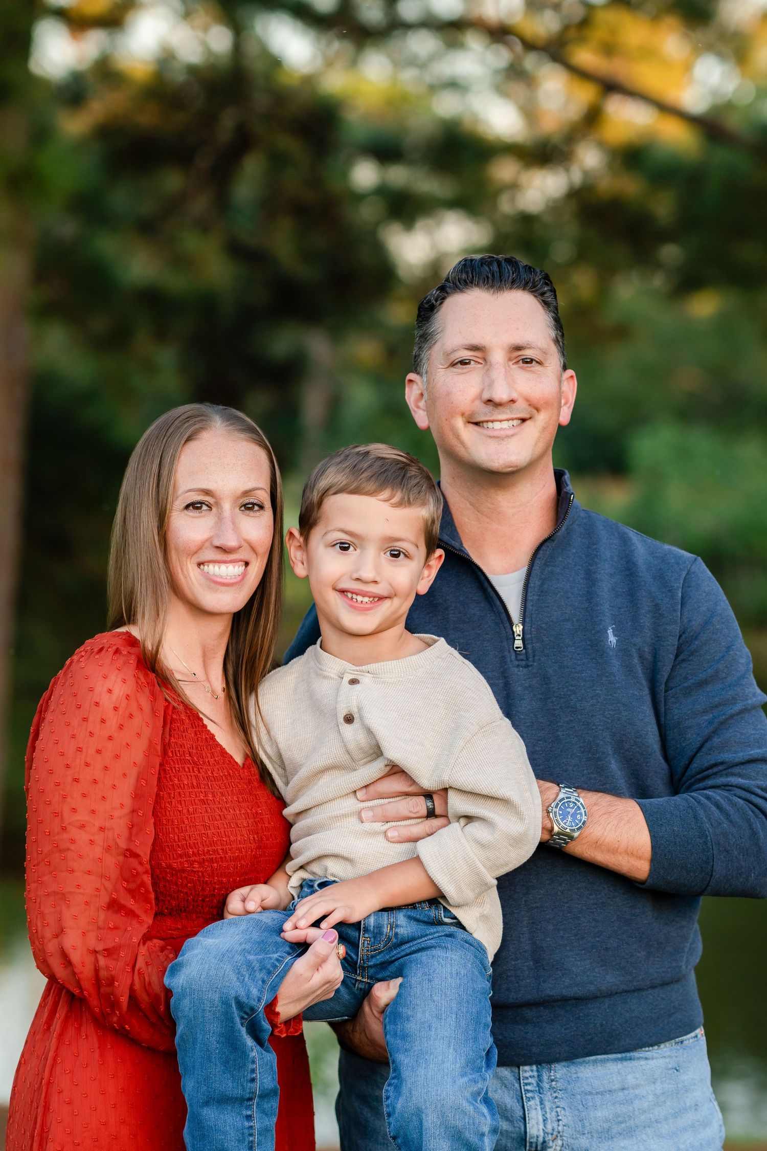 Family in coordinated blue and orange outfits poses together outdoors for casual autumn portrait session.