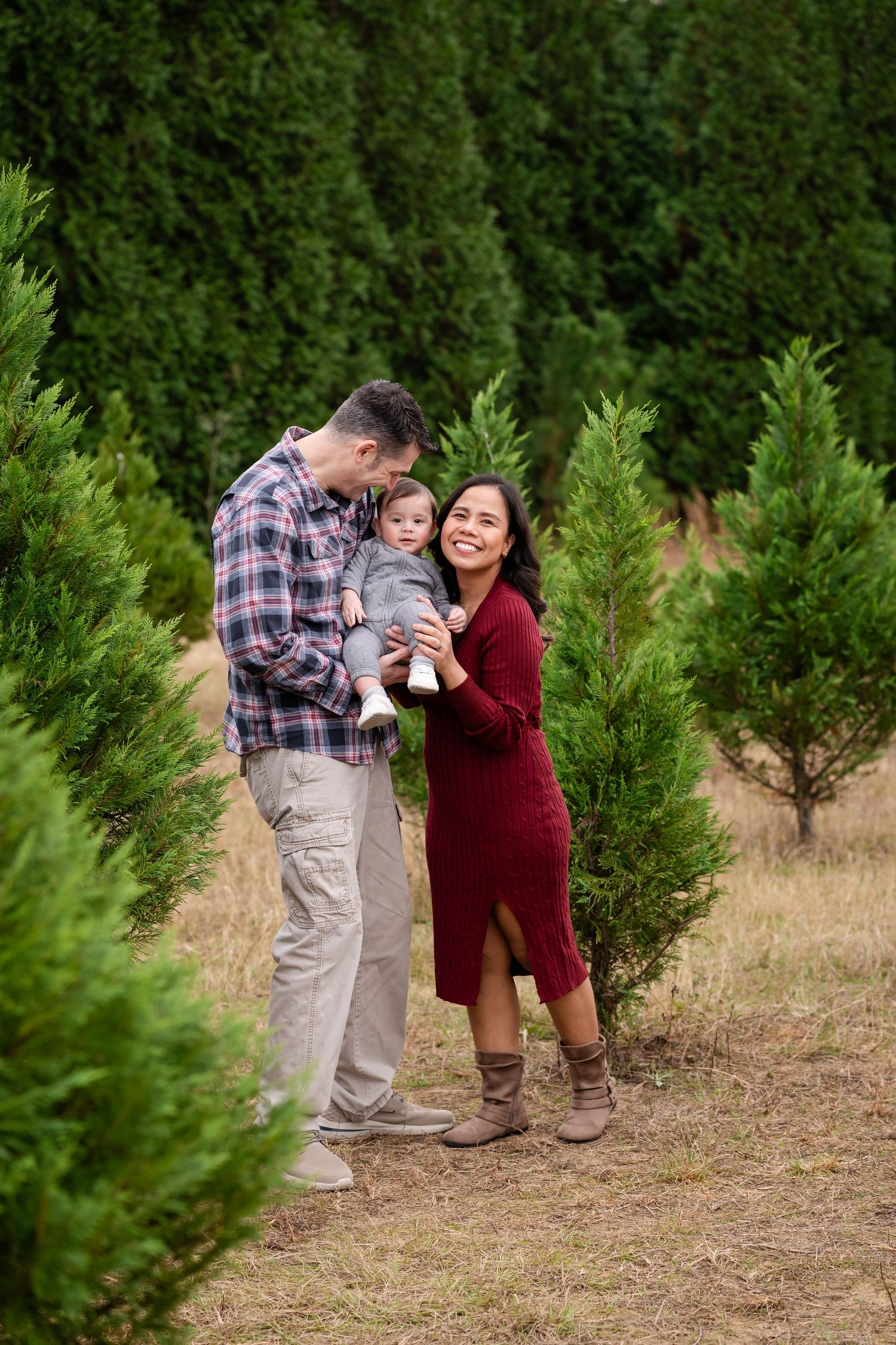 Candid family moments captured between evergreen trees on a sunny day.