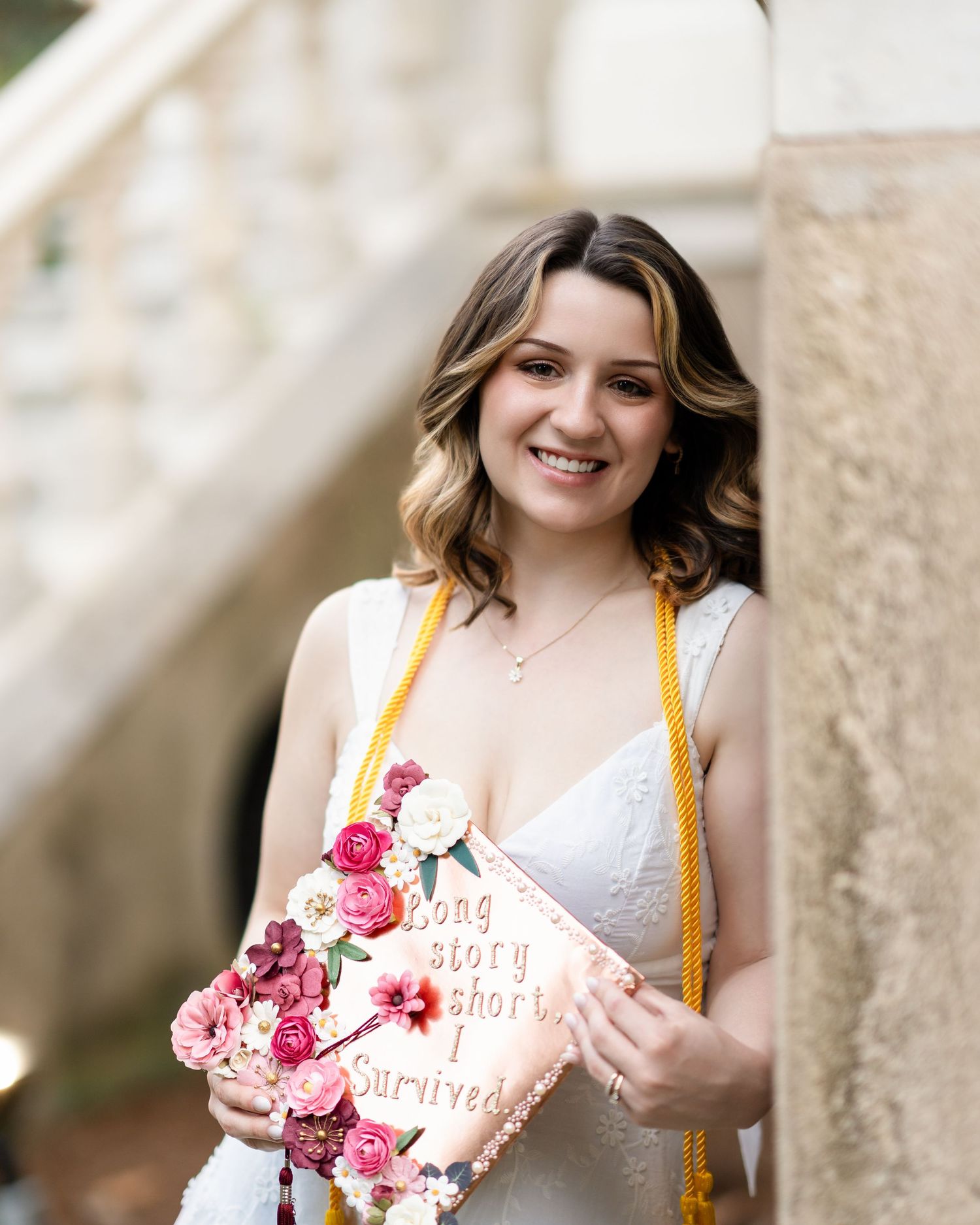 Person holding decorated book with floral accents against classical stone architecture.