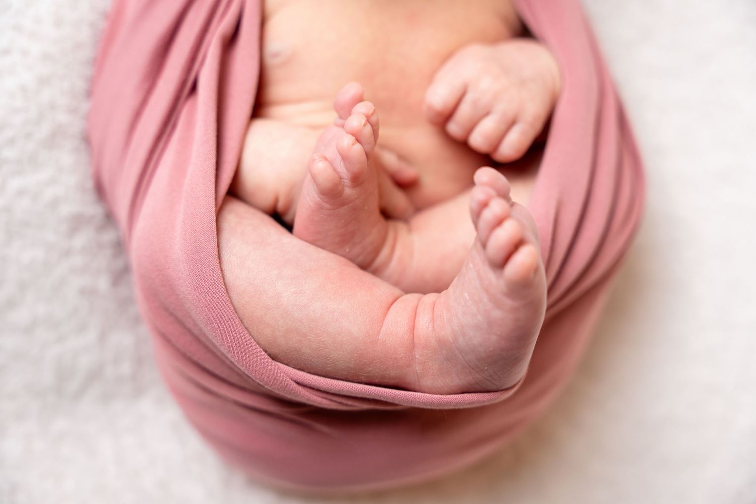 Soft pink fabric wrap creates an artistic swirl pattern on white background.