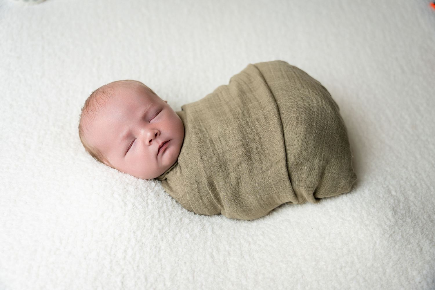 Sleeping newborn baby wrapped in beige cloth photographed from different angles.