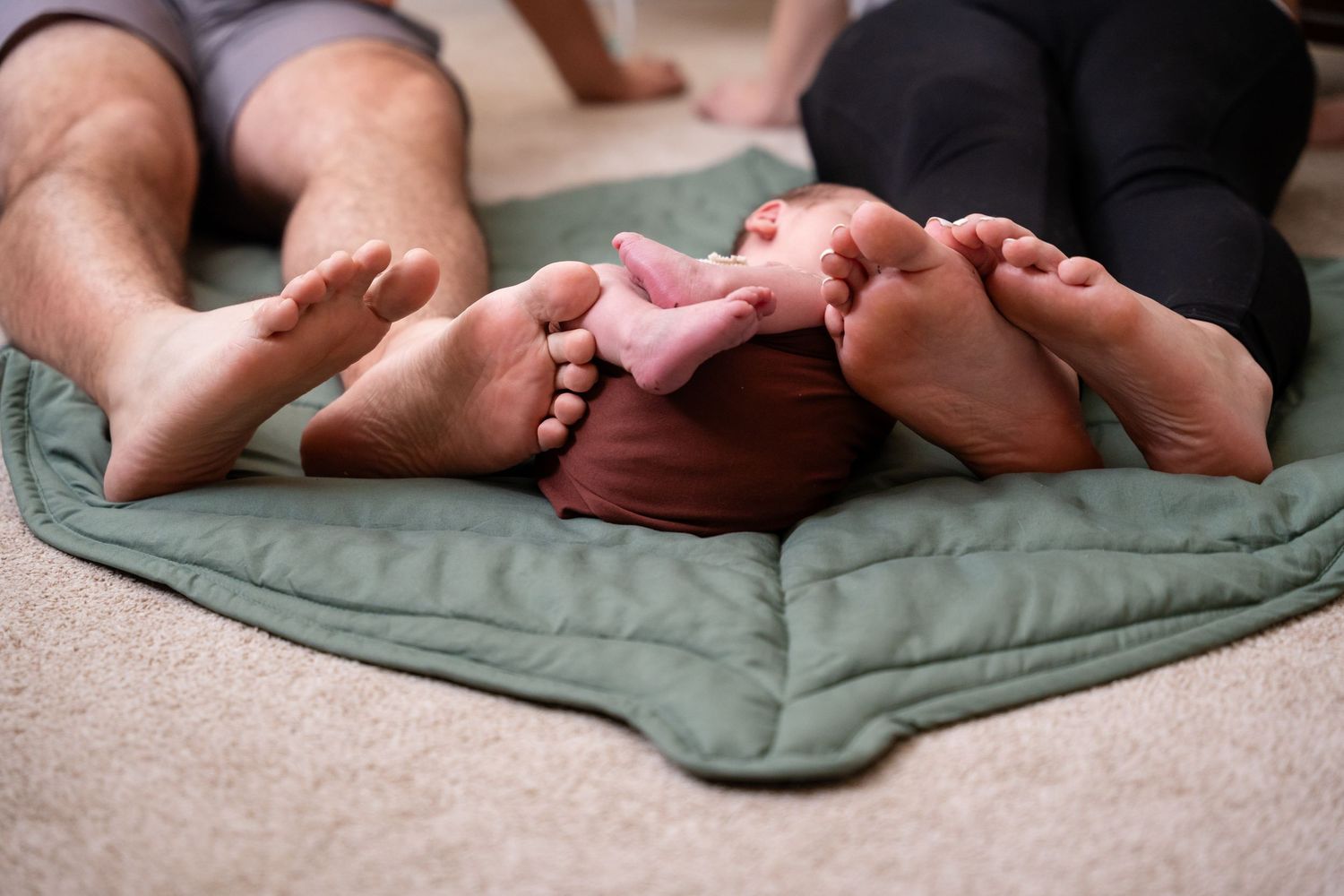 Baby feet resting on green cushion in natural light.