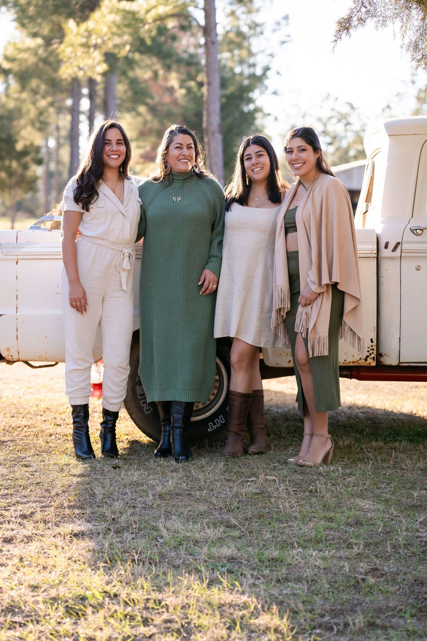 Friends in coordinated outfits standing together by classic truck in forest setting.