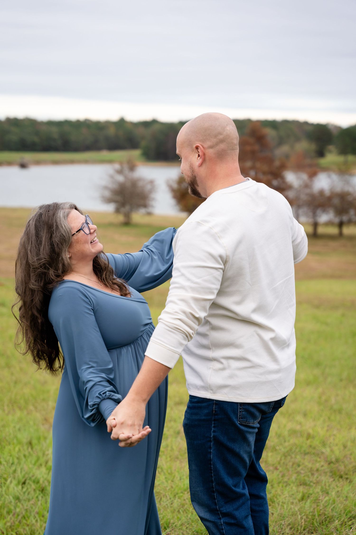 Playful maternity photoshoot moments captured in grassy field setting.