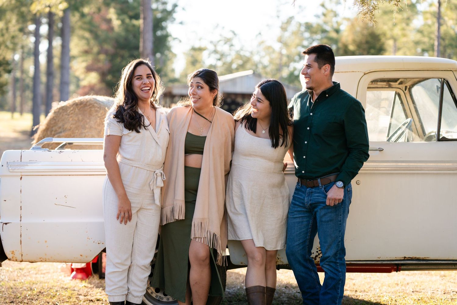 Family portrait session with vintage car as backdrop in outdoor setting.