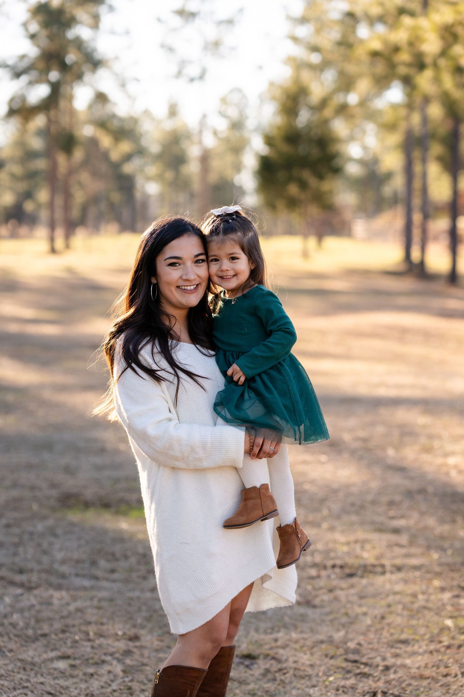Sweet moment captured outdoors with green dress and white sweater in autumn setting.