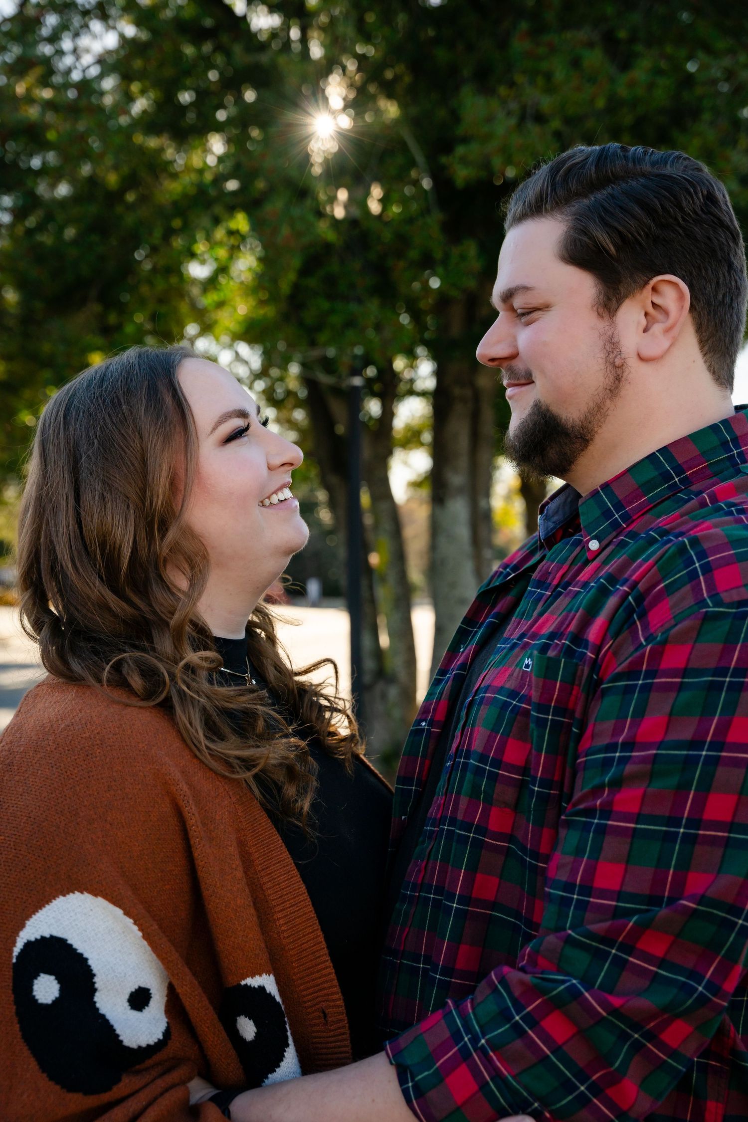 Couple sharing a laugh while wearing a plaid shirt and sweater with yin-yang design.
