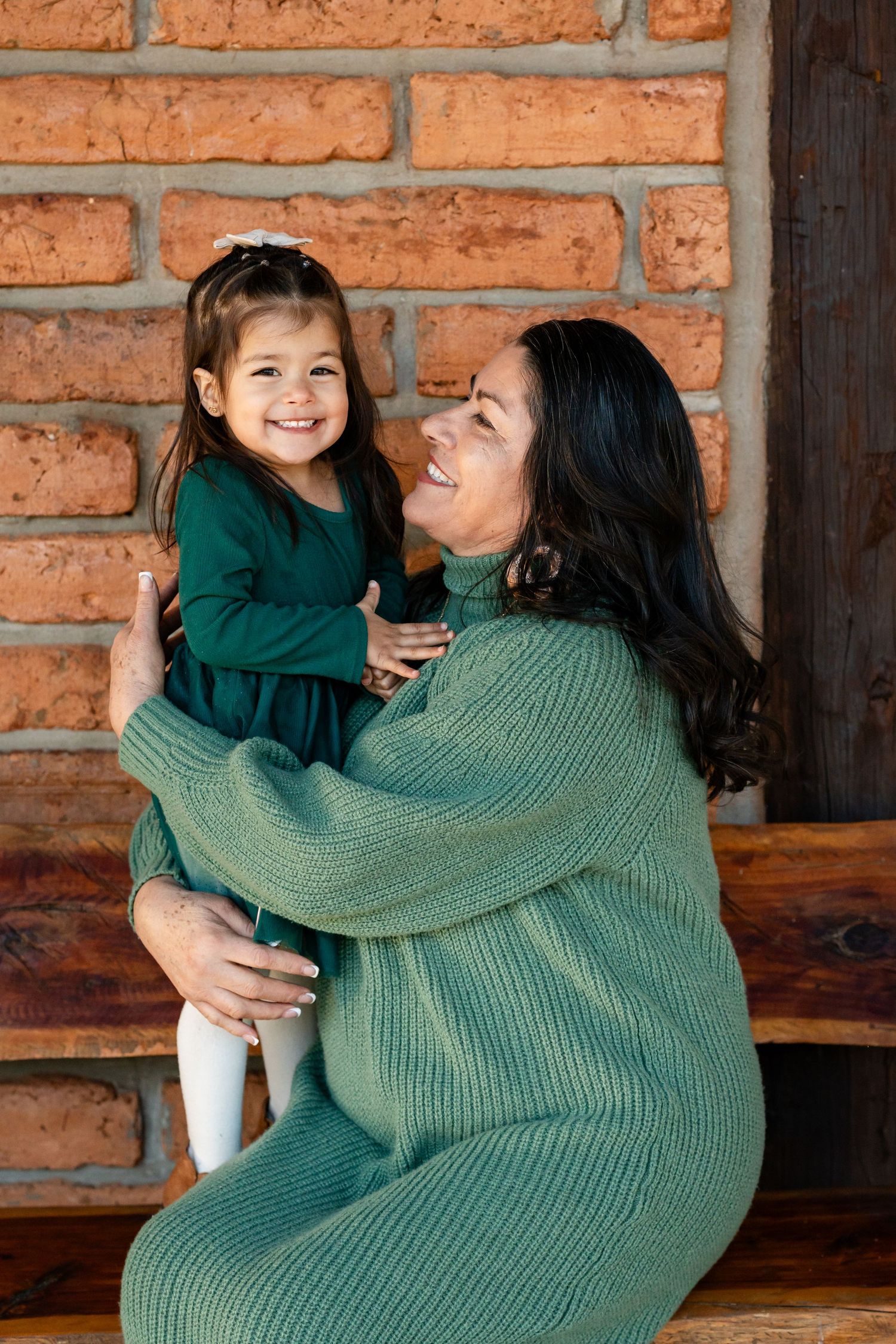 Parent and child sharing tender moments against brick wall backdrop.