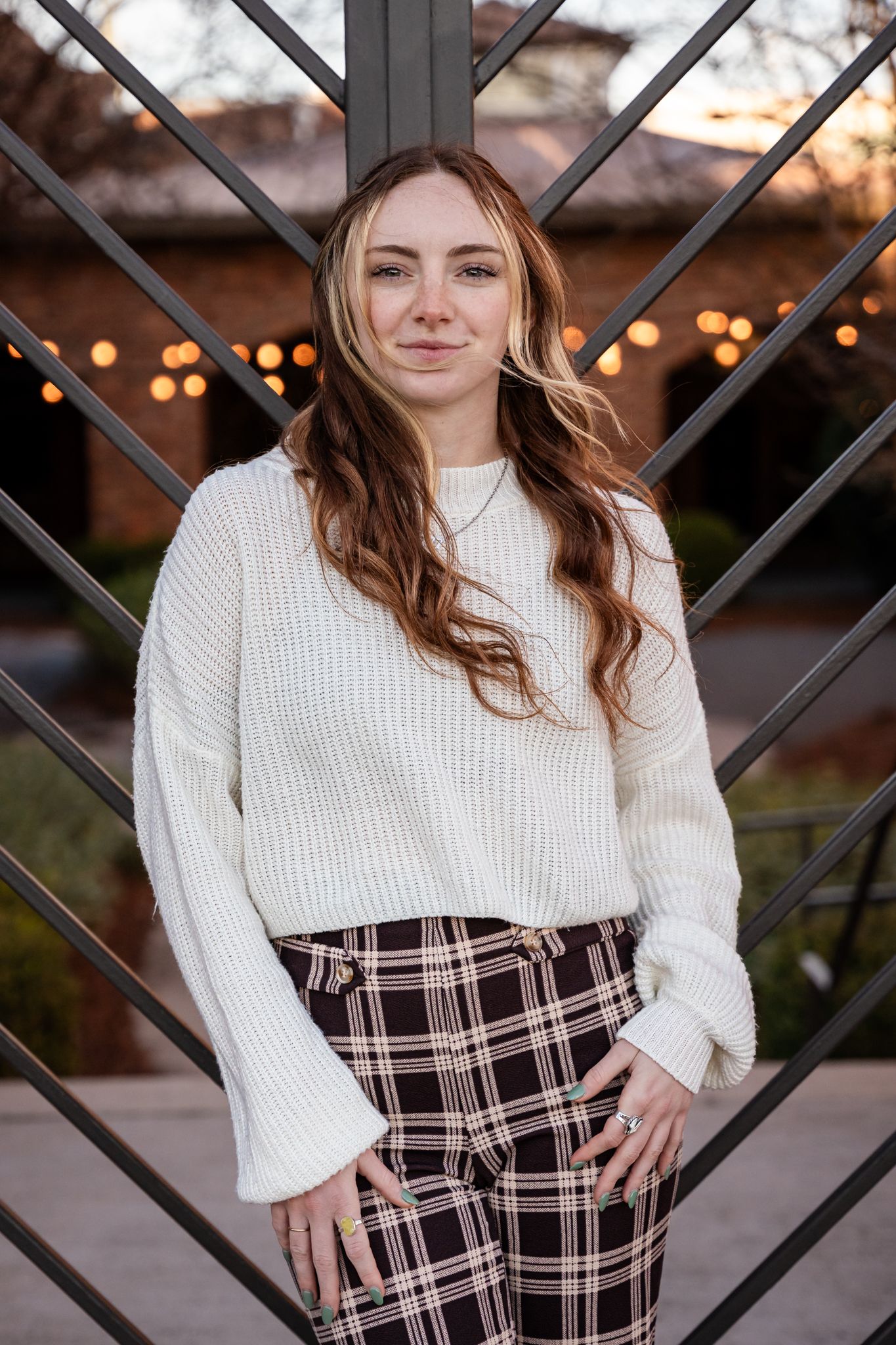 Urban fashion photography against geometric metal backdrop featuring winter outfit with plaid pants.