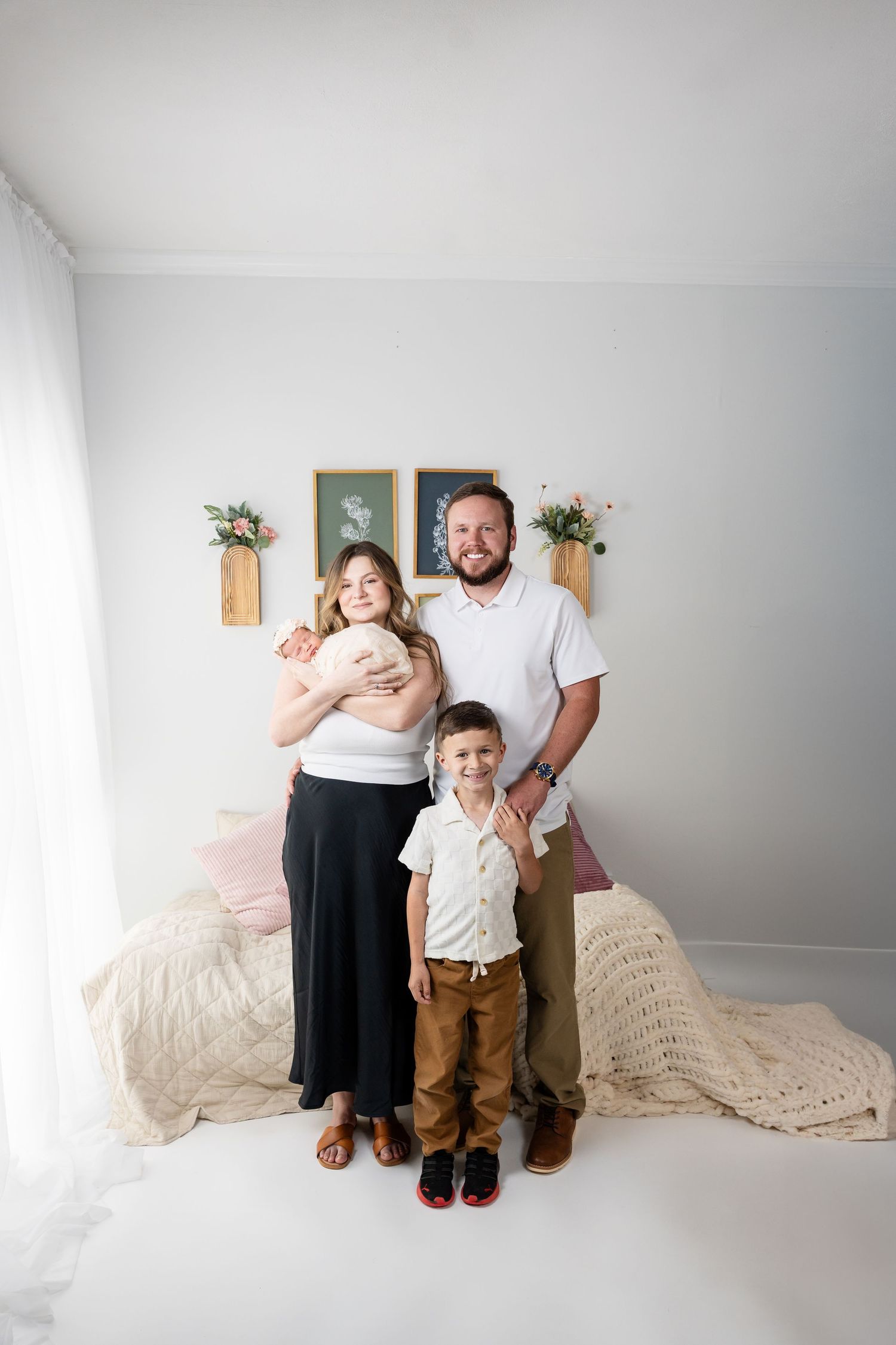 Family portrait session in neutral colors against white backdrop with decorative elements.