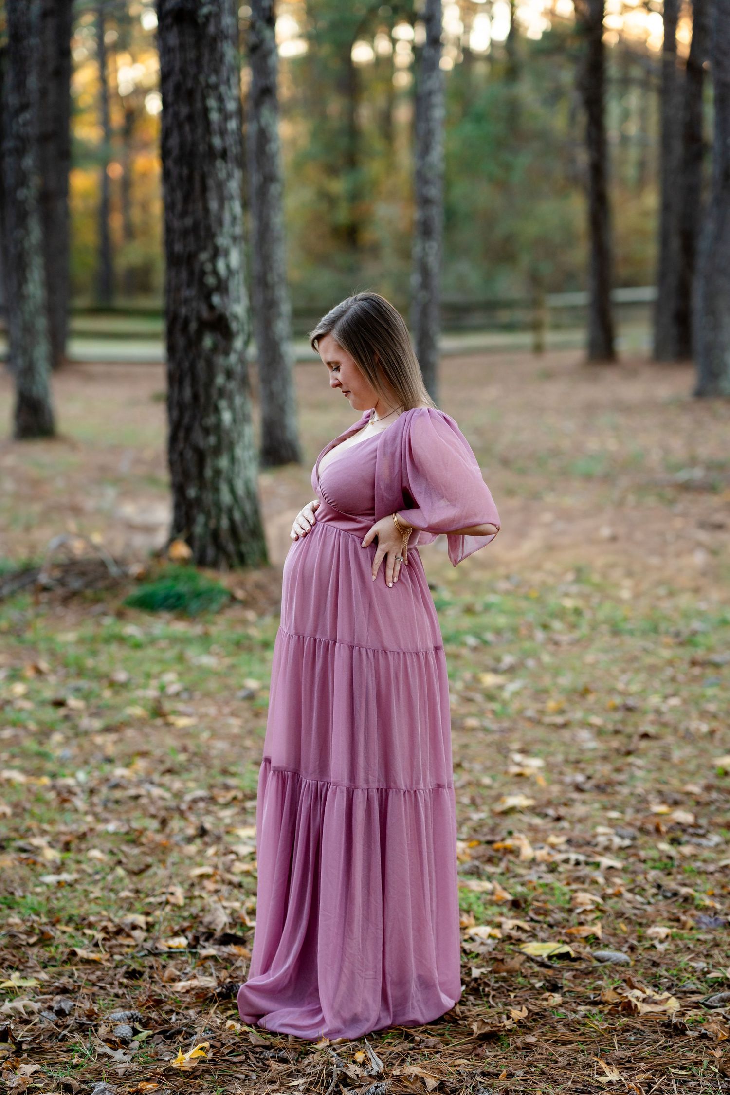 A flowing mauve dress catches light in a serene forest setting.