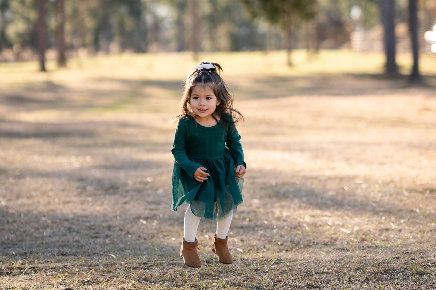 Toddler in green dress exploring outdoors on an autumn day.