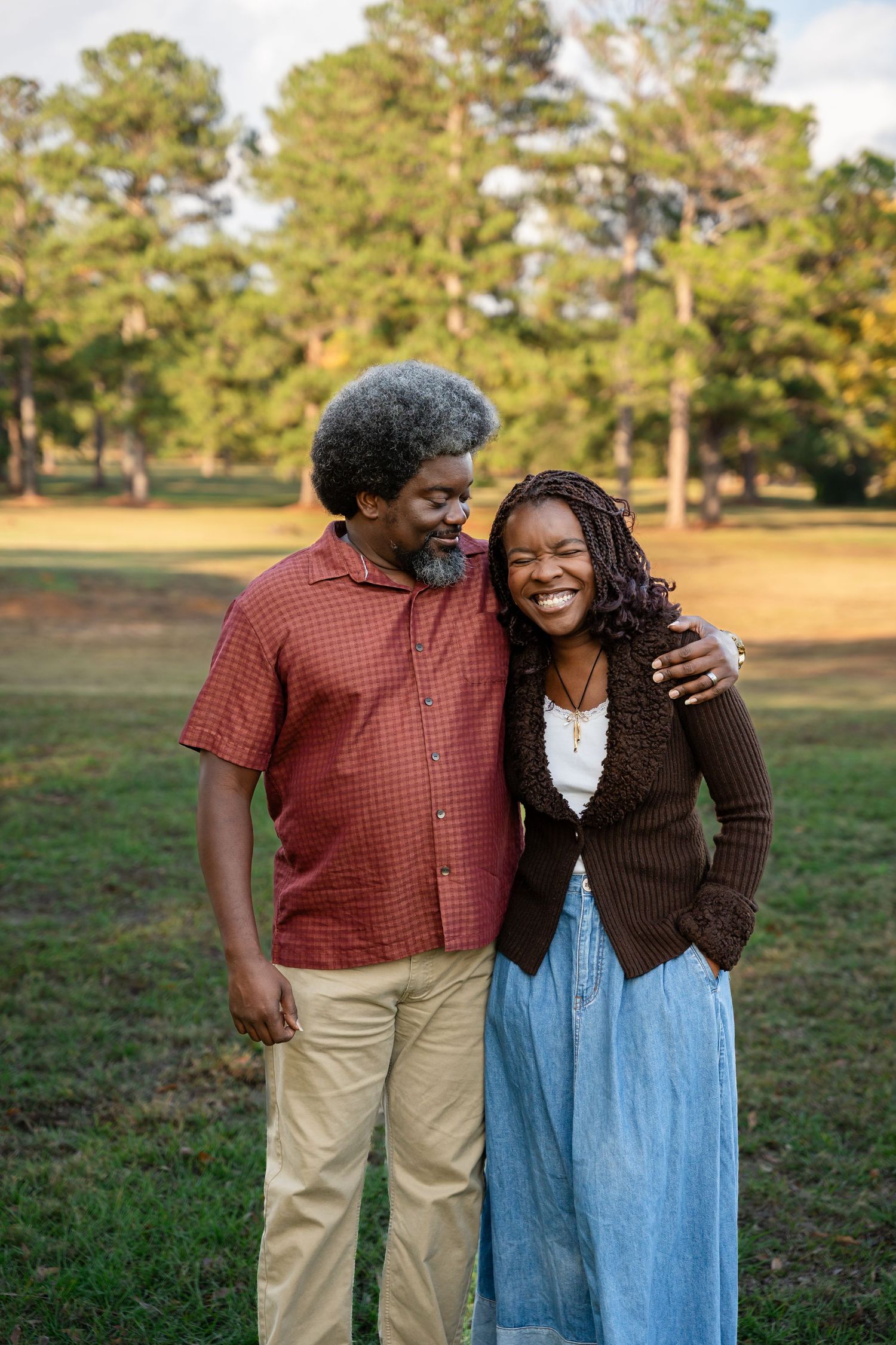 Two people embracing and laughing together in an outdoor park setting.