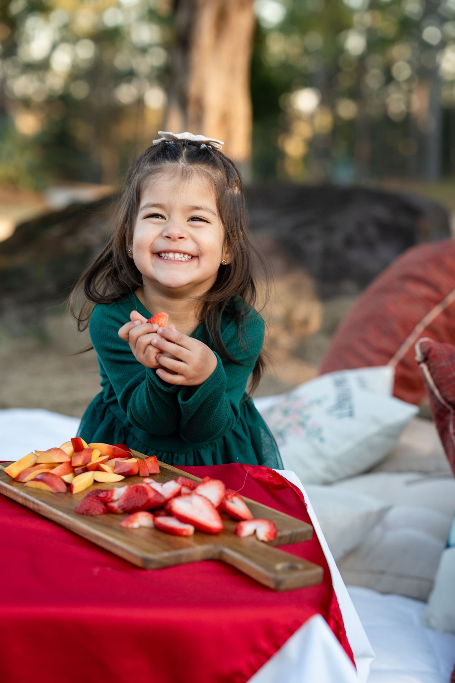 A joyful moment captured with fresh fruit slices on a red picnic blanket outdoors.