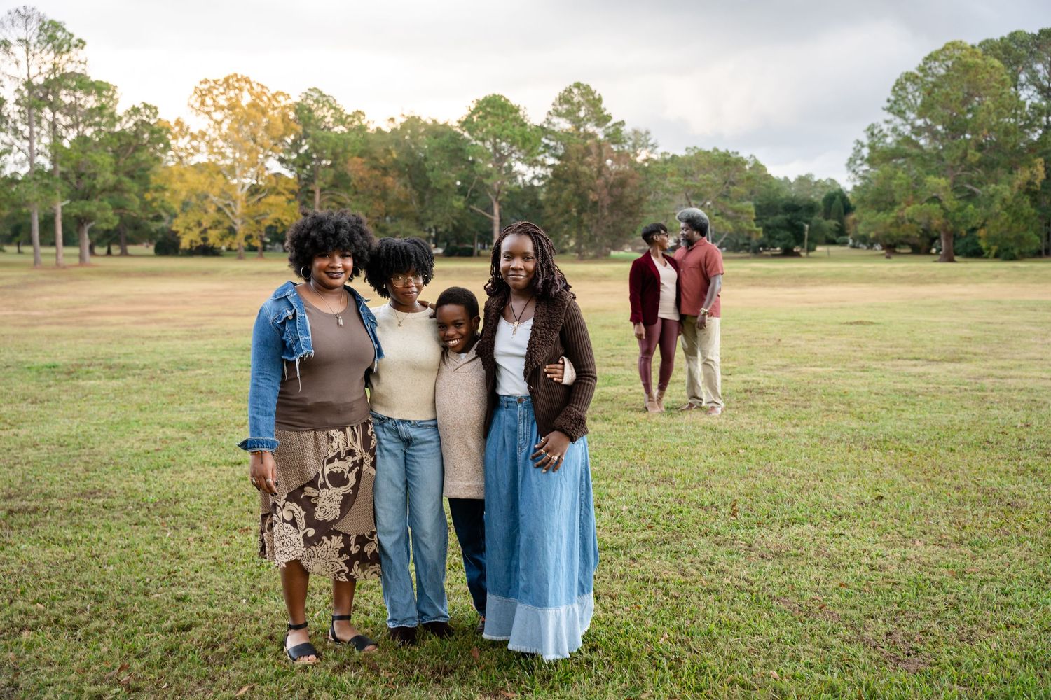 Group gathered for outdoor photos in a spacious park with autumn trees.