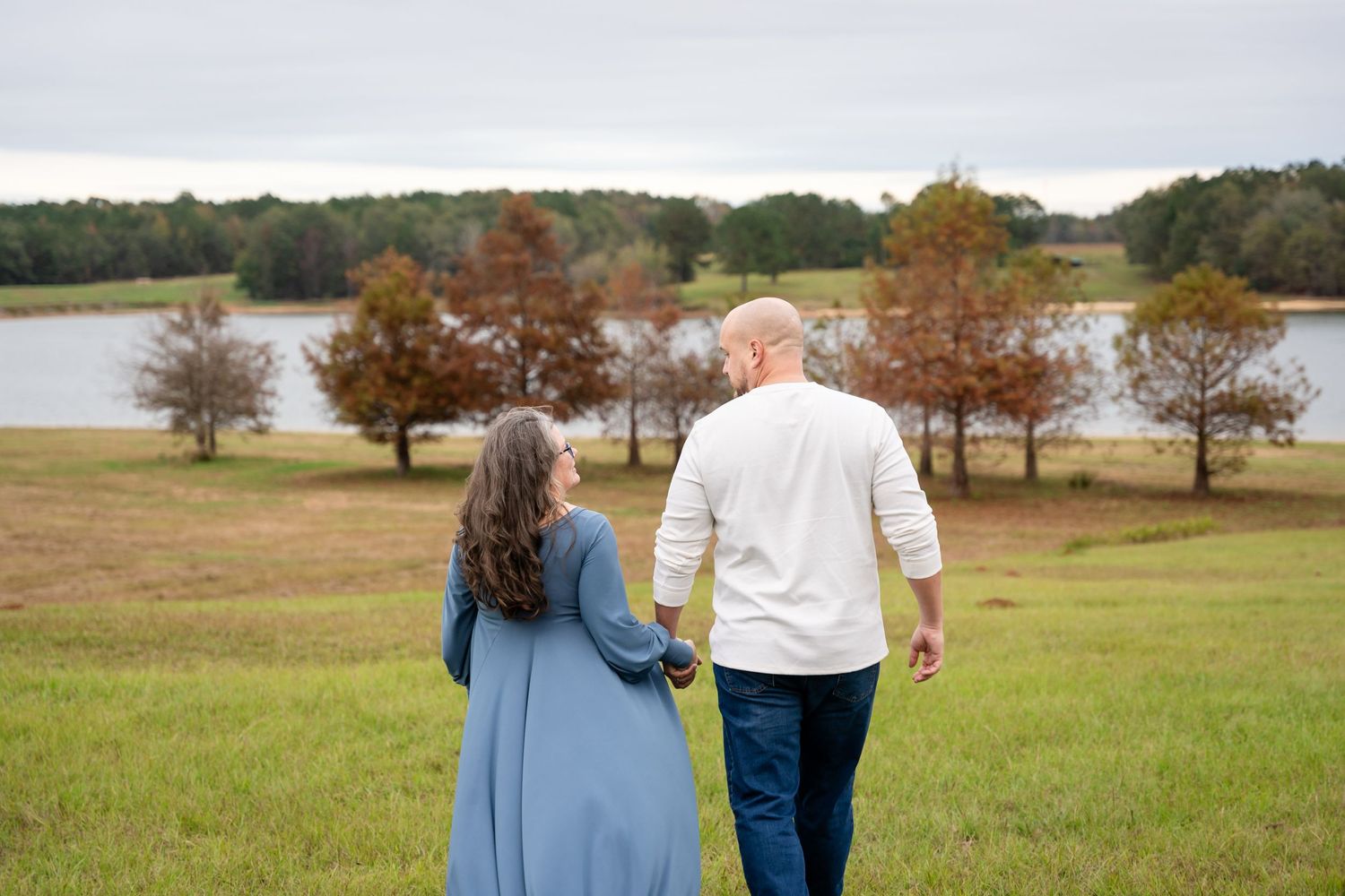 Wide landscape maternity photos showing couple against scenic autumn backdrop.