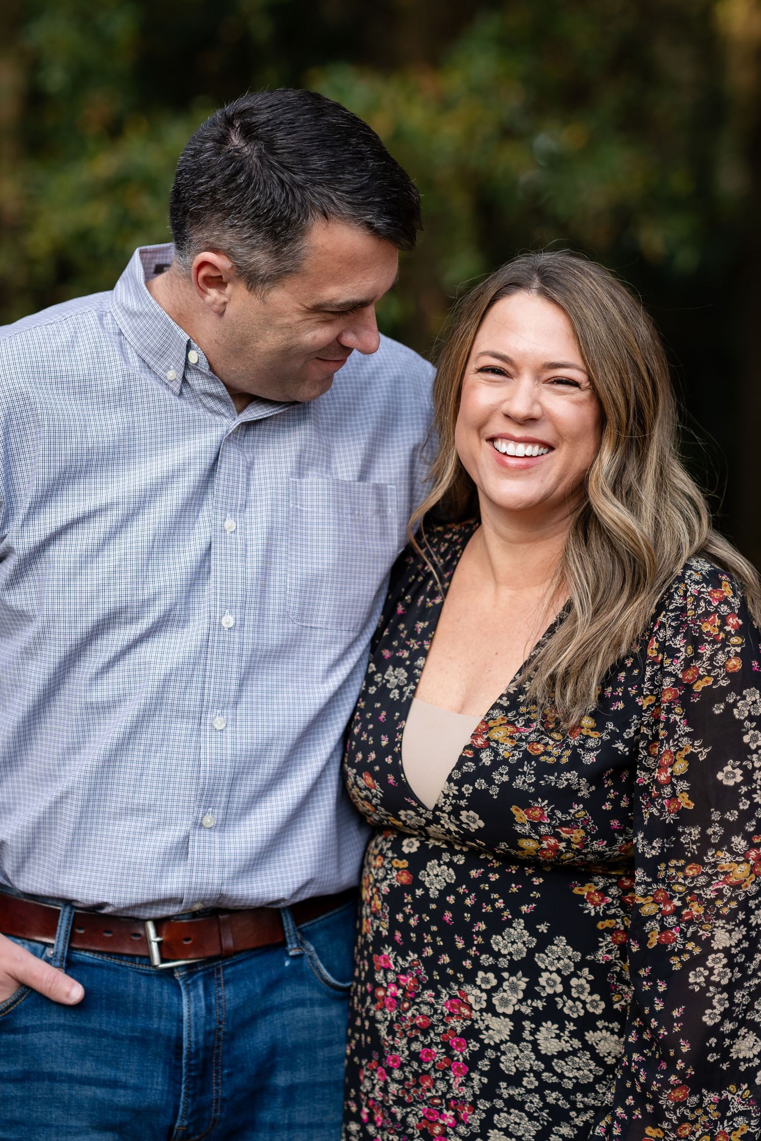 Romantic couple laughing together during outdoor autumn photoshoot.