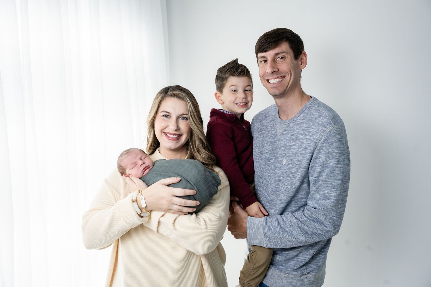 Family sitting together in a bright studio wearing coordinating casual outfits for a portrait session.