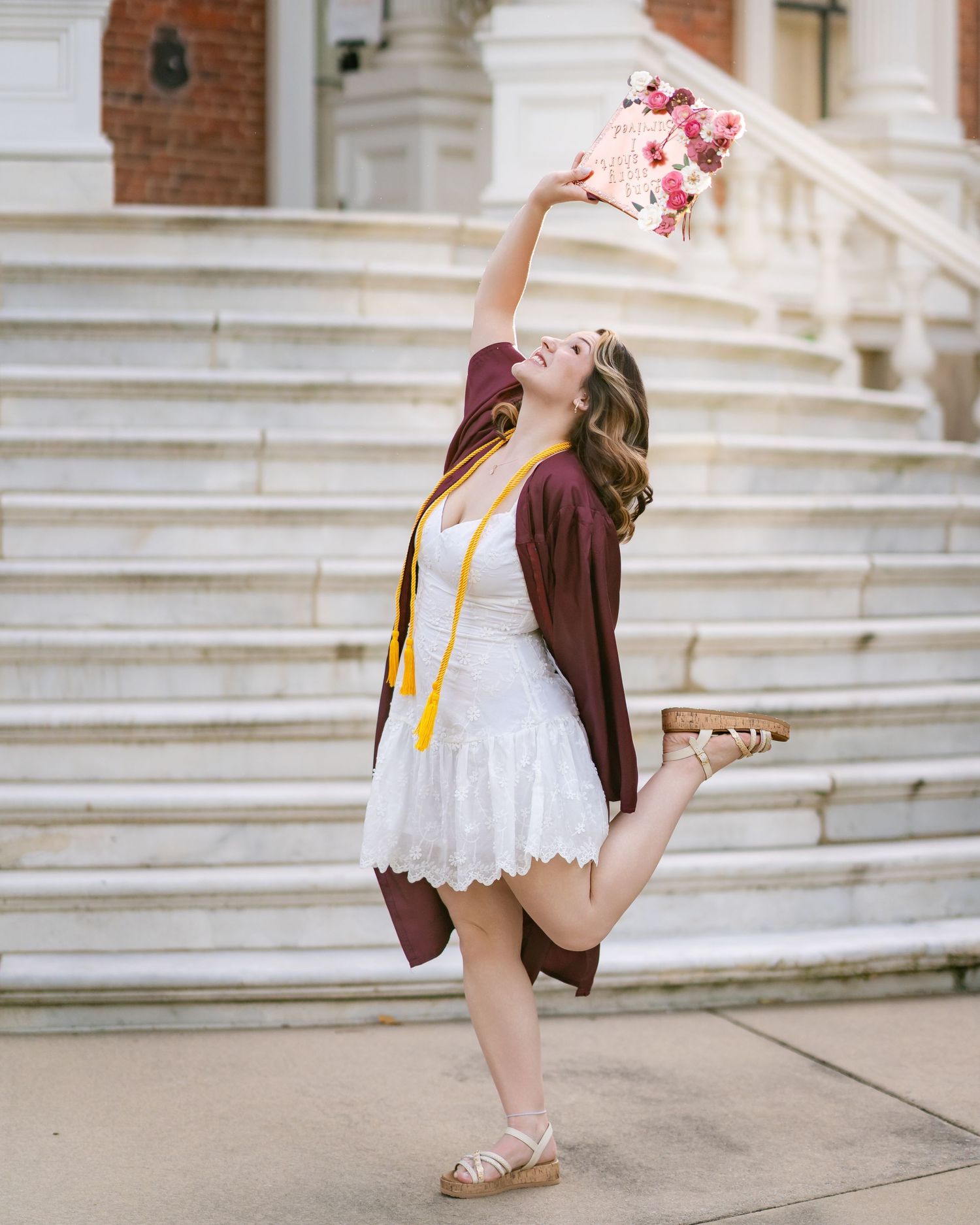 Figure in white dress and burgundy jacket walking down grand marble steps with backpack.