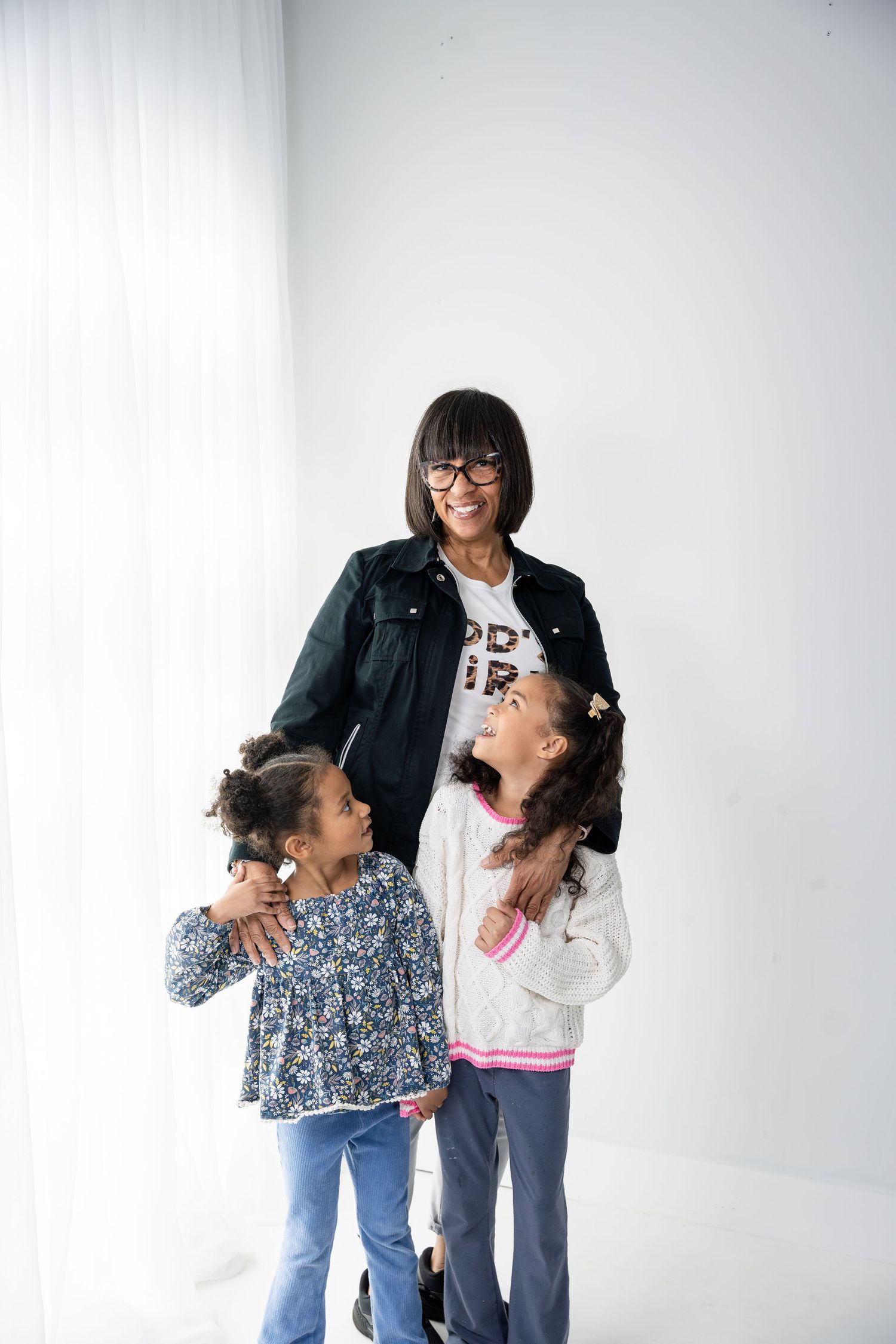 Candid family portrait session with joyful interactions against white studio background.
